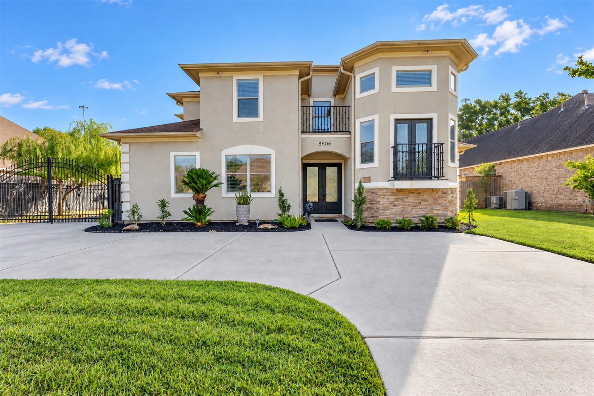8606 Argentina Street, Houston, TX 77040 Striking curb appeal with an elegant stucco and stone exterior, two charming balconies, and a gated driveway. Double entry doors create a welcoming first impression.