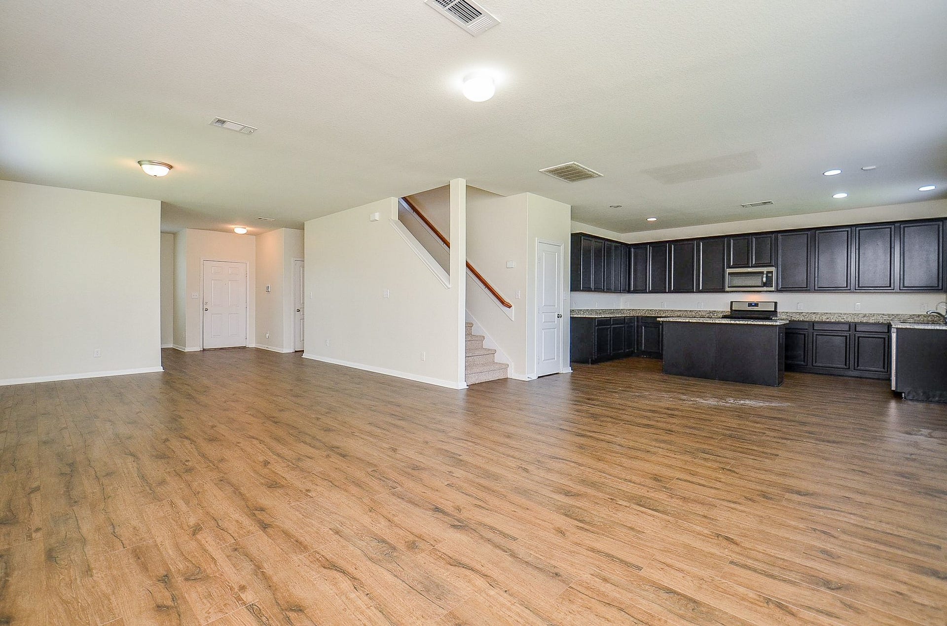 2539 Bedrock Lane, Missouri City, TX 77489 Spacious open-concept living area with elegant flooring, modern kitchen featuring dark cabinetry, and a seamless flow to the dining space.