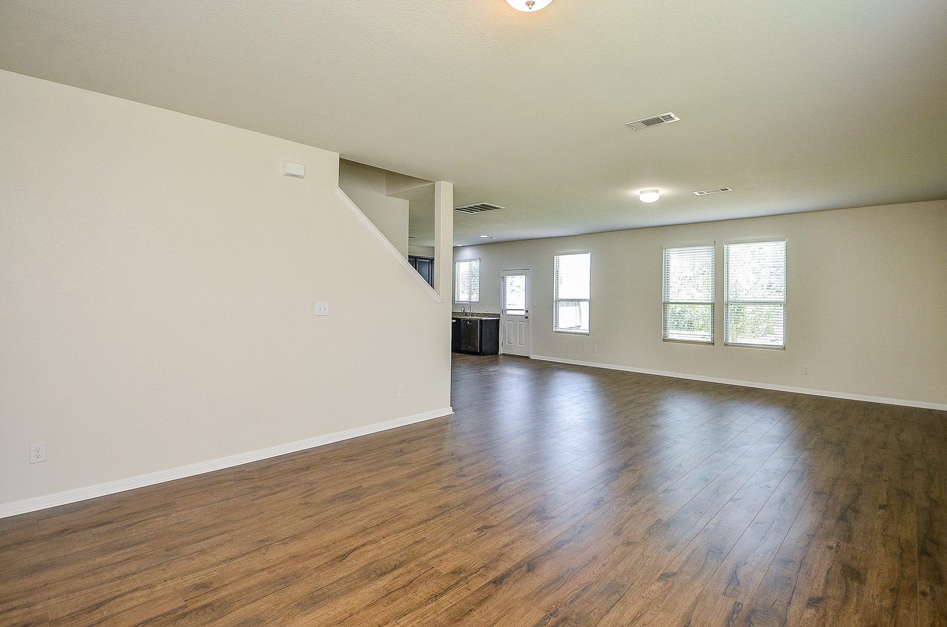 2539 Bedrock Lane, Missouri City, TX 77489 Spacious open-concept living area featuring elegant wood flooring, abundant natural light from large windows, and a view into the kitchen area, perfect for entertaining and family gatherings.