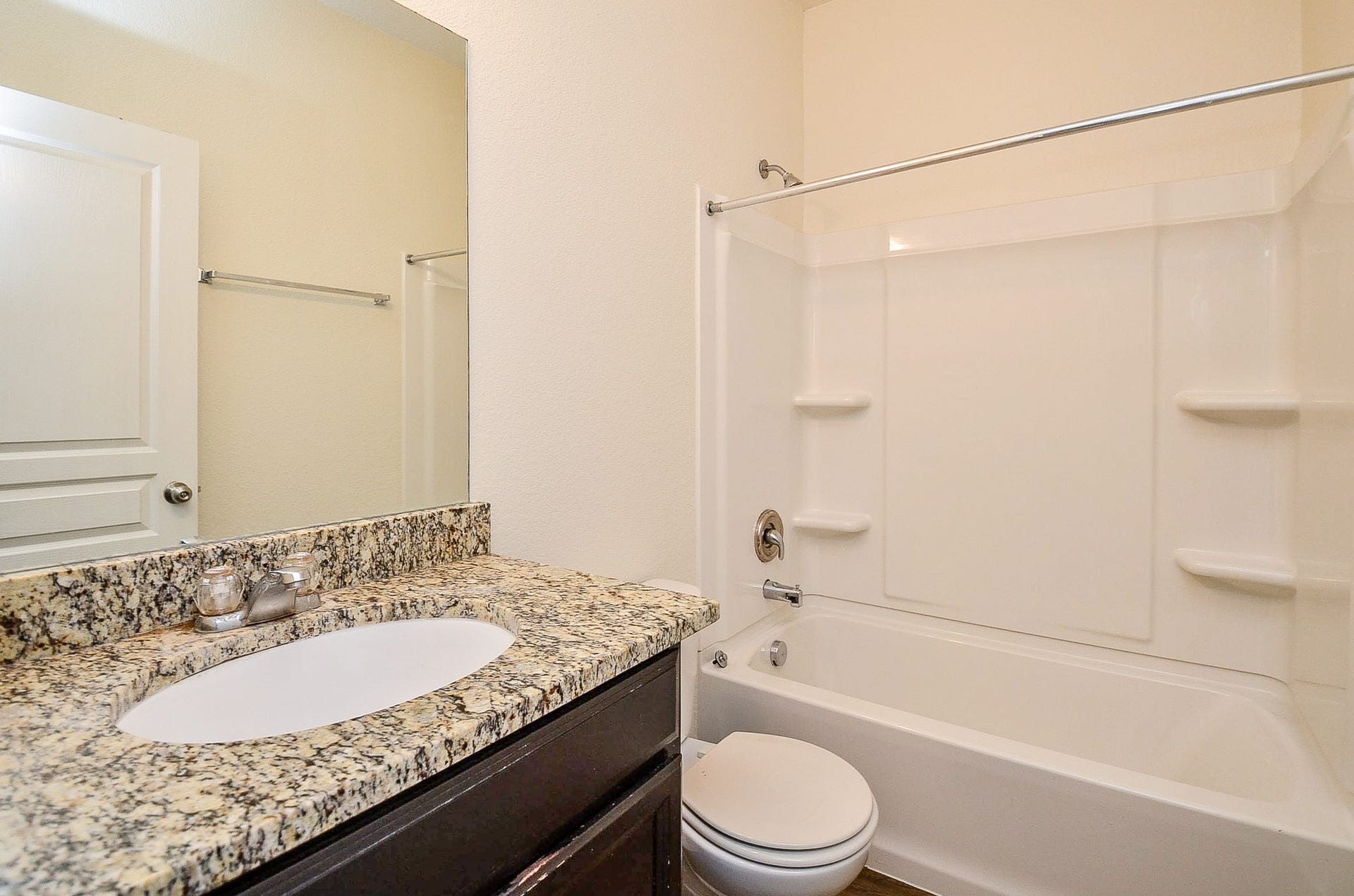 2539 Bedrock Lane, Missouri City, TX 77489 Bathroom featuring a sleek granite countertop with an undermount sink, a full bathtub with shelving, and warm flooring.