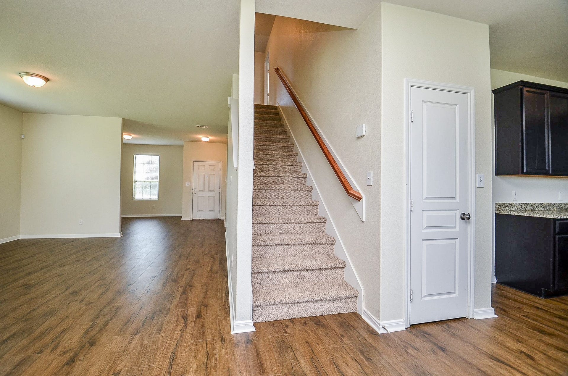 2539 Bedrock Lane, Missouri City, TX 77489 Inviting open-concept space with rich flooring, featuring a central staircase, bright living area, and a glimpse of the modern kitchen with sleek cabinetry.