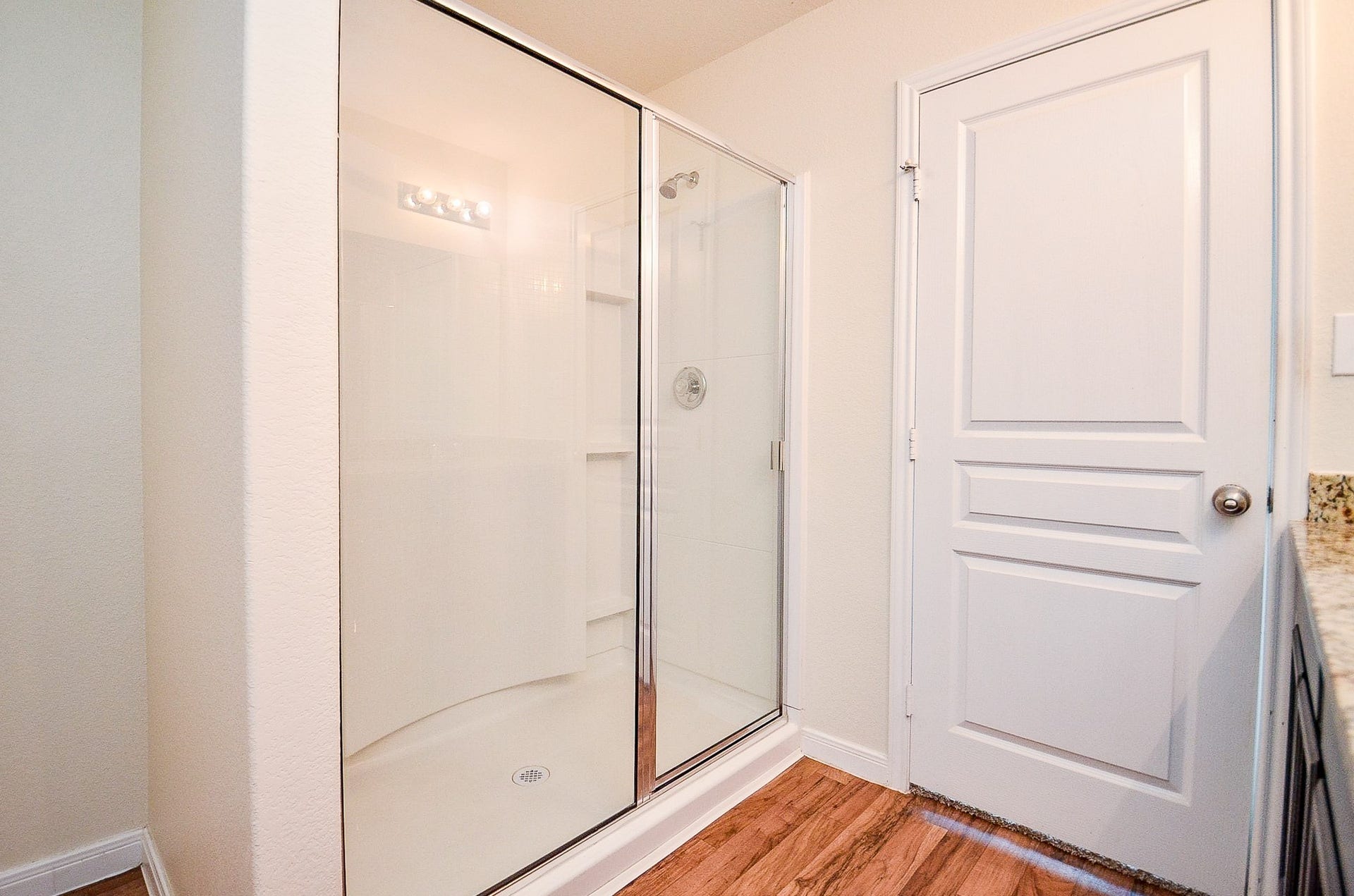 2539 Bedrock Lane, Missouri City, TX 77489 Spacious walk-in shower with sleek glass doors, complemented by warm flooring and a modern white interior.