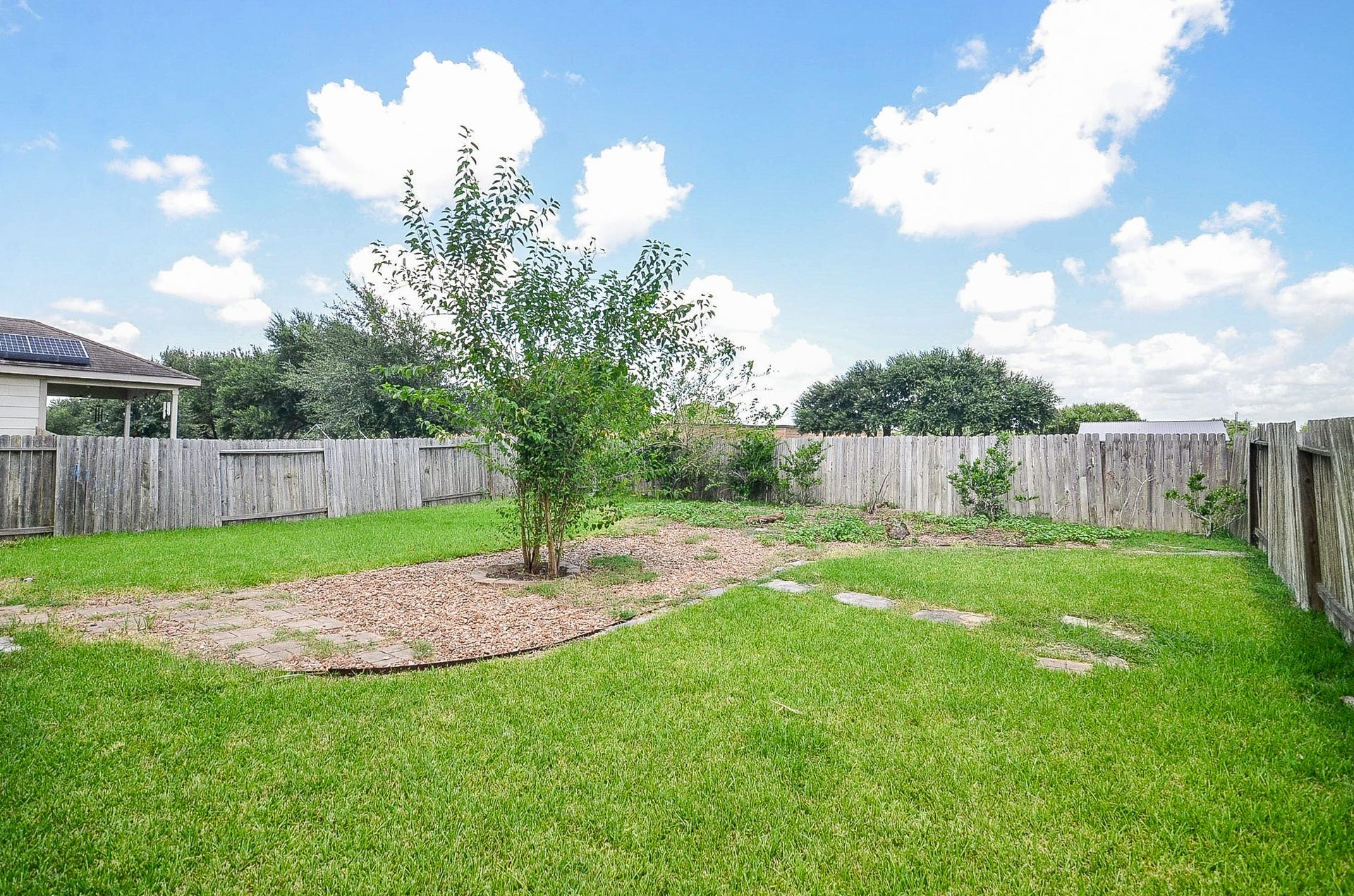 2539 Bedrock Lane, Missouri City, TX 77489 Spacious backyard with lush green grass, a small tree, and a wooden fence for privacy, perfect for outdoor activities and relaxation.