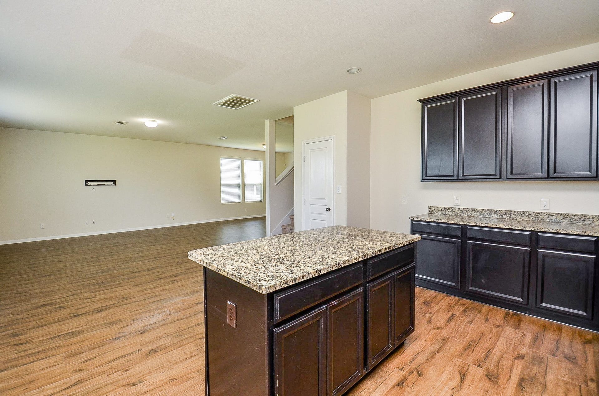 2539 Bedrock Lane, Missouri City, TX 77489 Spacious open-concept living area with rich flooring and a modern kitchen featuring granite countertops and dark cabinetry, perfect for entertaining or family gatherings.