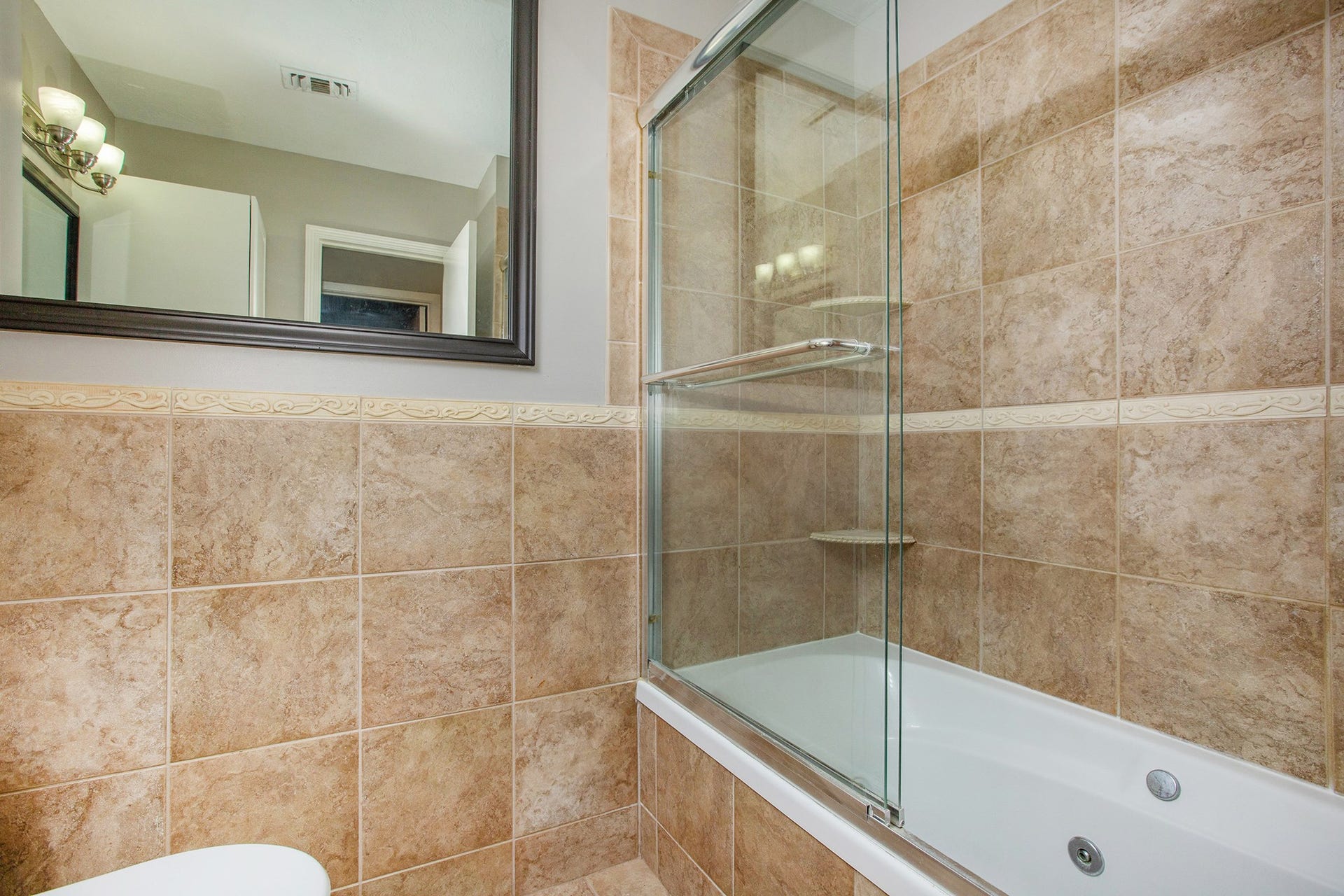 17002 Sky Blue Place, Houston, TX 77095 Guest bathroom features granite countertop, framed mirror, tub/shower combination with whirlpool jets.