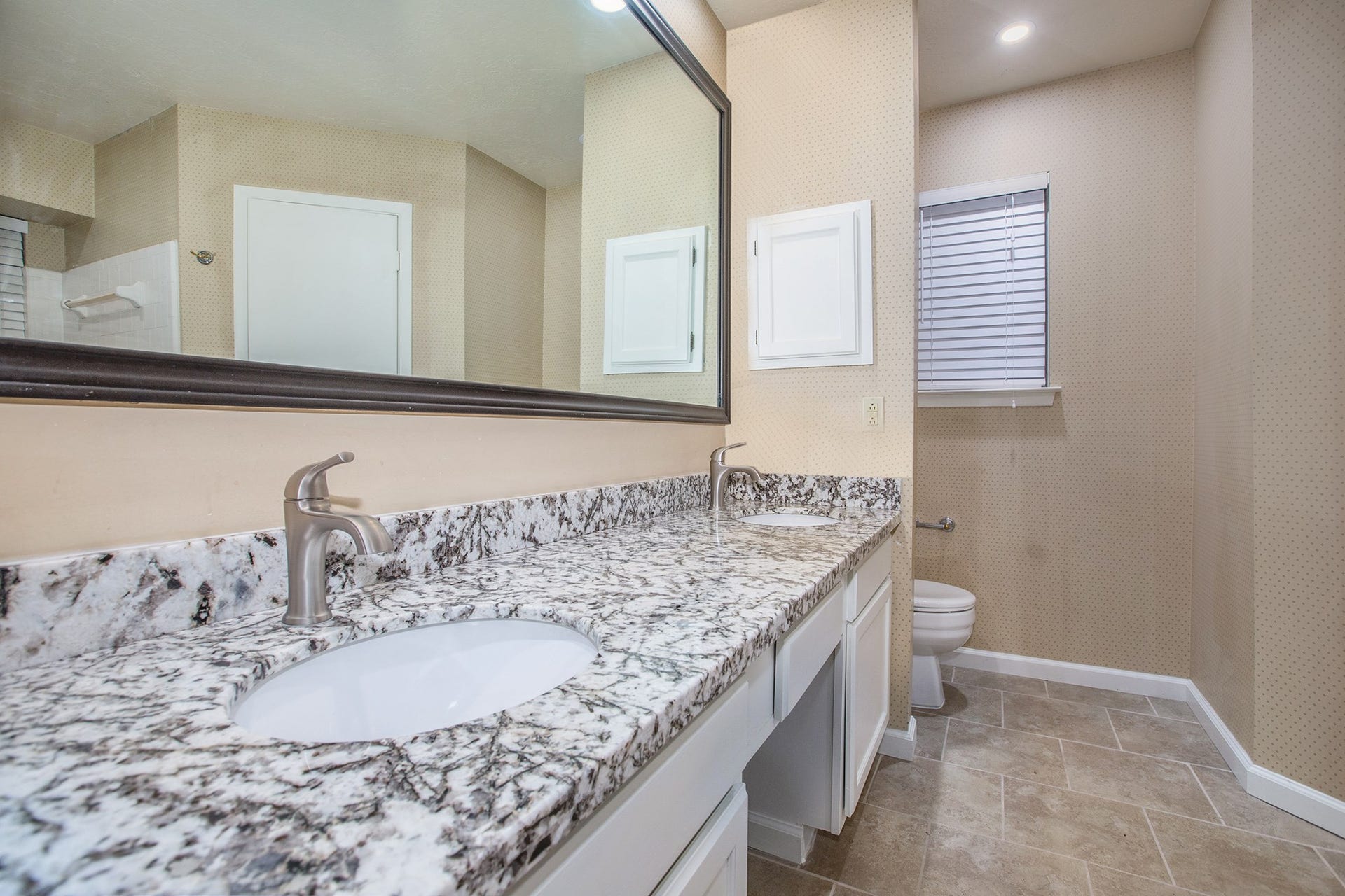 17002 Sky Blue Place, Houston, TX 77095 Master bathroom features granite countertop with dual sinks and faucets, framed mirror, white cabinets and tile flooring.
