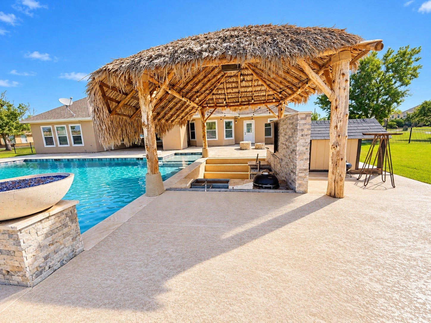 8999 Water Point Drive, Beach City, TX 77523 Luxurious outdoor oasis featuring a sparkling pool, poolside cabana with a thatched roof, and built-in entertainment area, perfect for relaxation and entertaining.