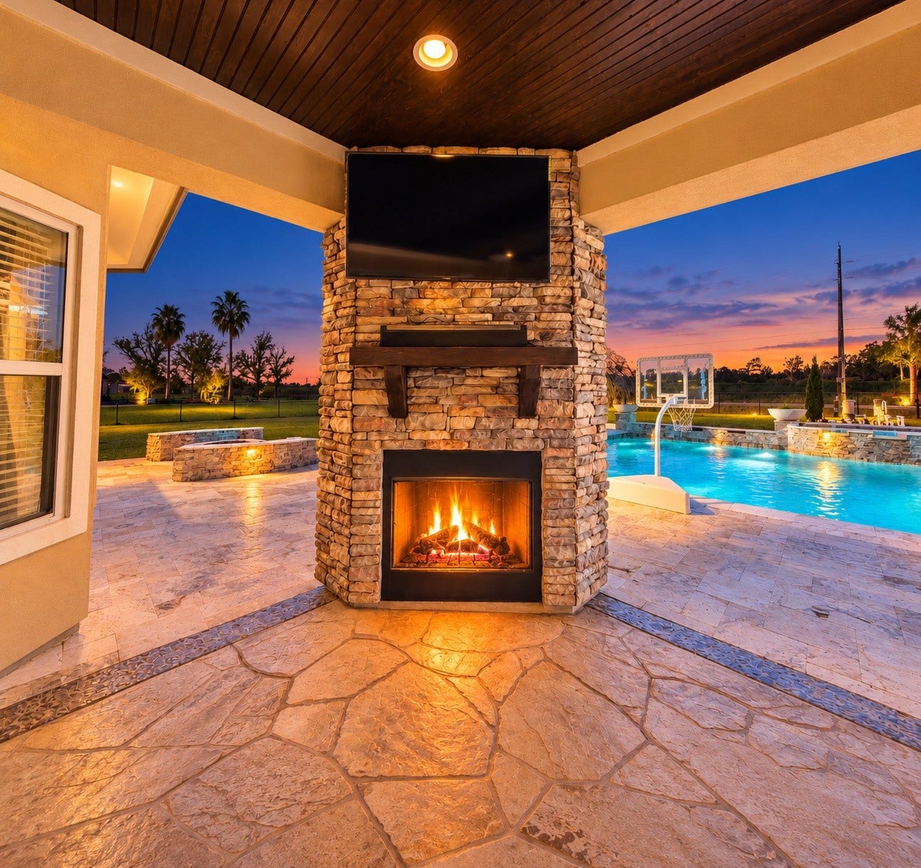 8999 Water Point Drive, Beach City, TX 77523 Experience outdoor luxury with a stunning stone fireplace and entertainment area, overlooking a sparkling pool and serene sunset views.