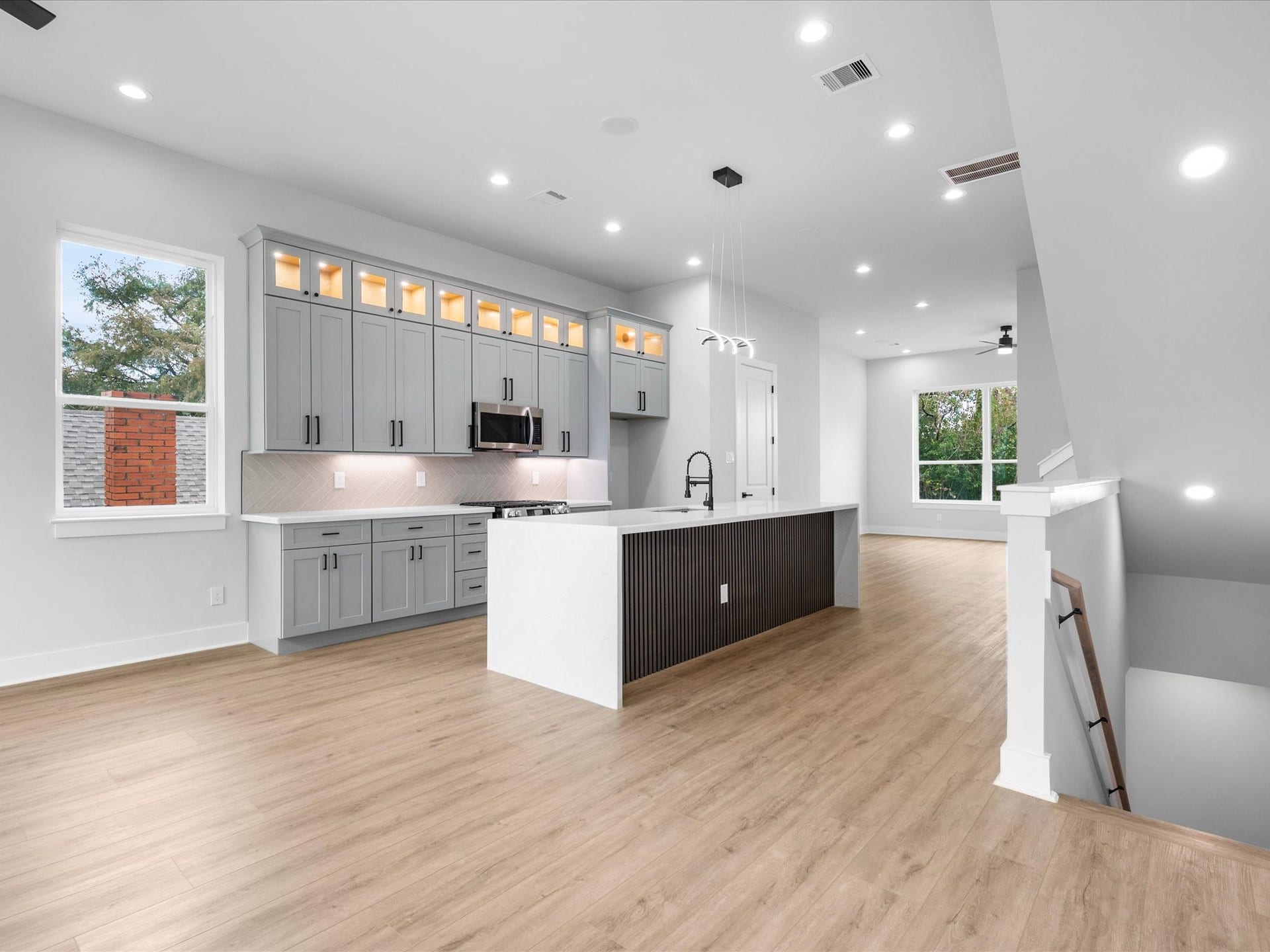 A sleek, contemporary kitchen anchors the living space with a striking waterfall island, quartz countertops, and refined finishes that make everyday living feel elevated.