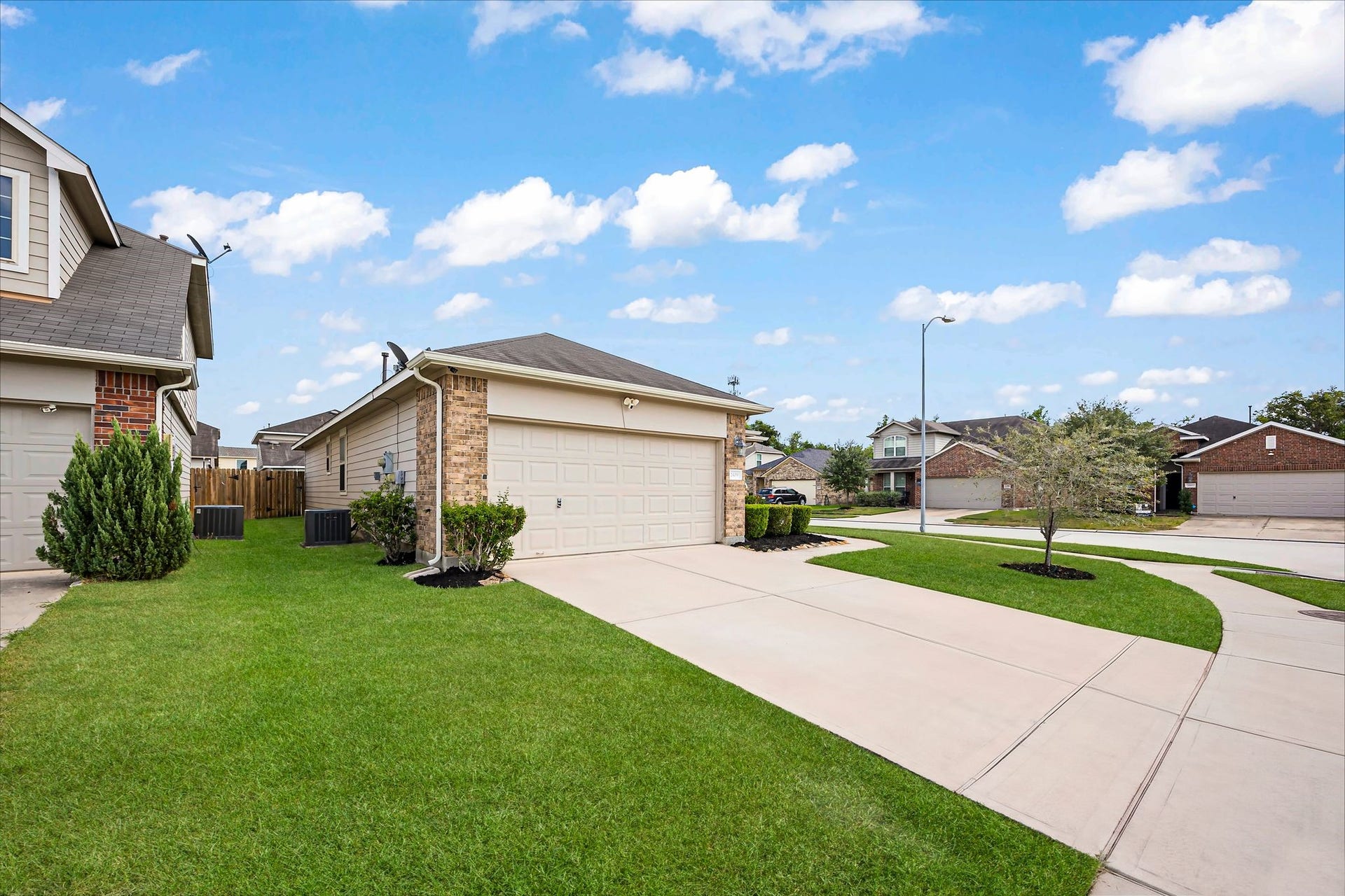 A welcoming first impression with a wide driveway, and a neatly framed front lawn.