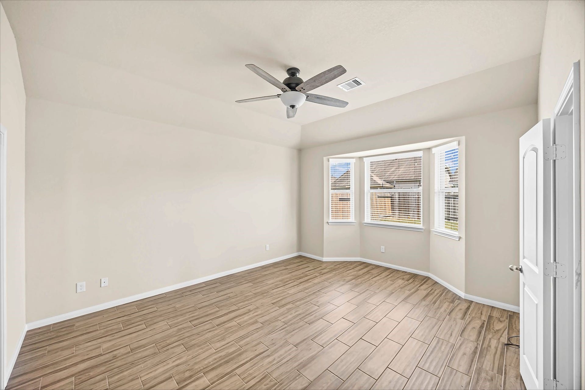 Retreat to a restful primary bedroom with a ceiling fan, natural light, and tile flooring.