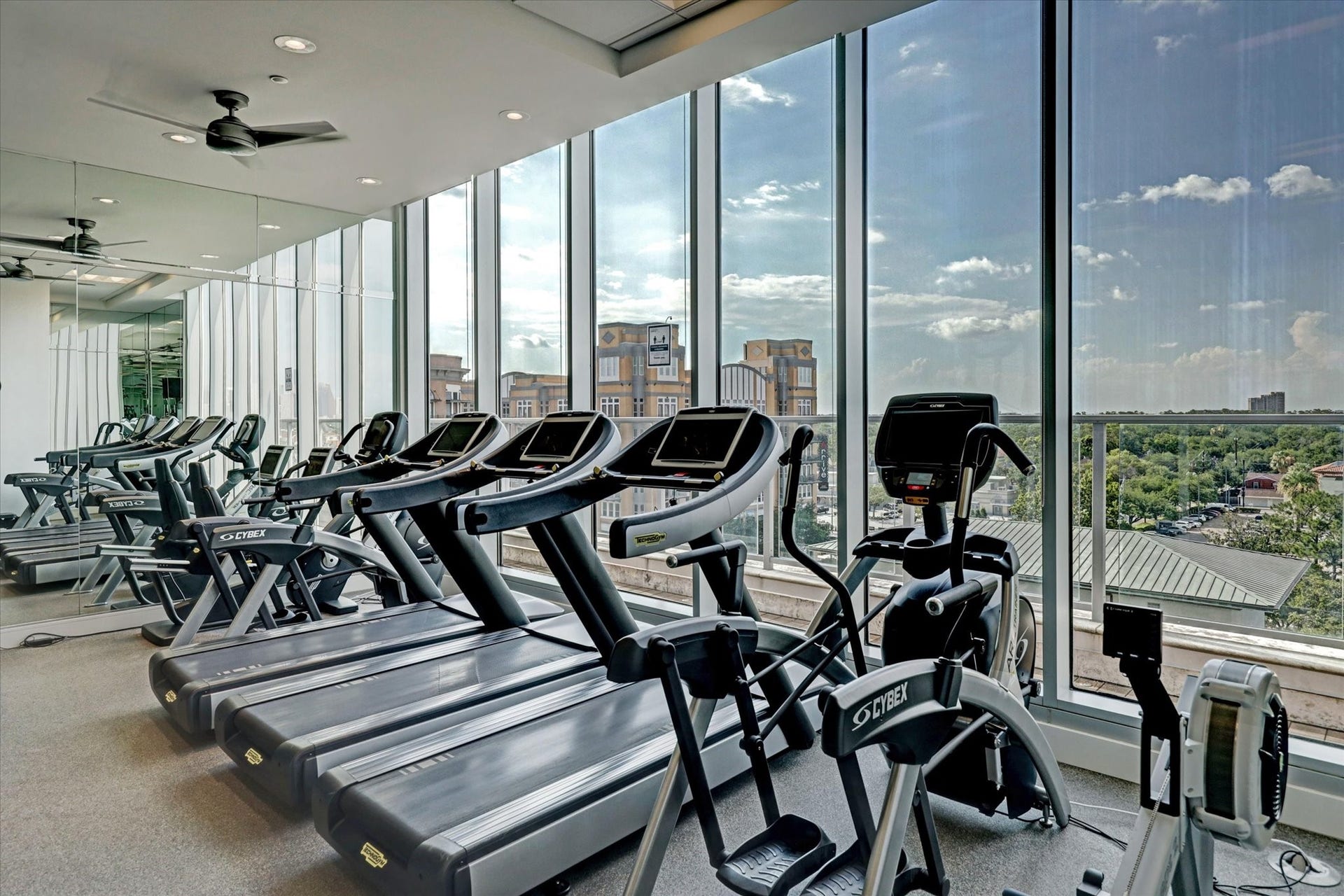 2727 Kirby Drive, #13E, Houston, TX 77098 Fitness area with Cybex equipment, mirrored walls, and floor-to-ceiling windows. Also features a Pilates studio, private spa, mens and womens steams room and massage rooms.