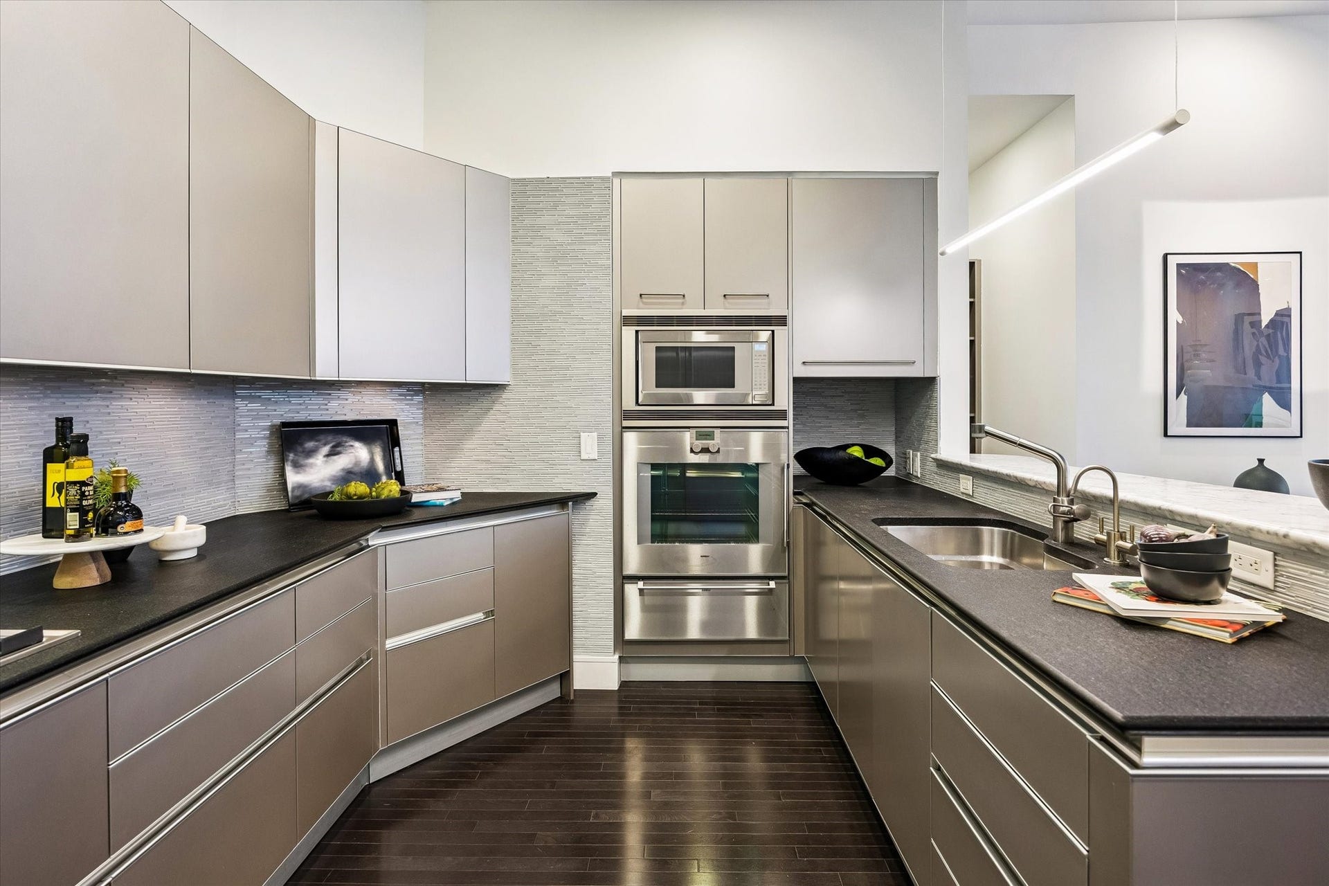 [Kitchen] The kitchen's U-shaped layout features extensive cabinetry, modern tile backsplash, and high-end stainless steel appliances.