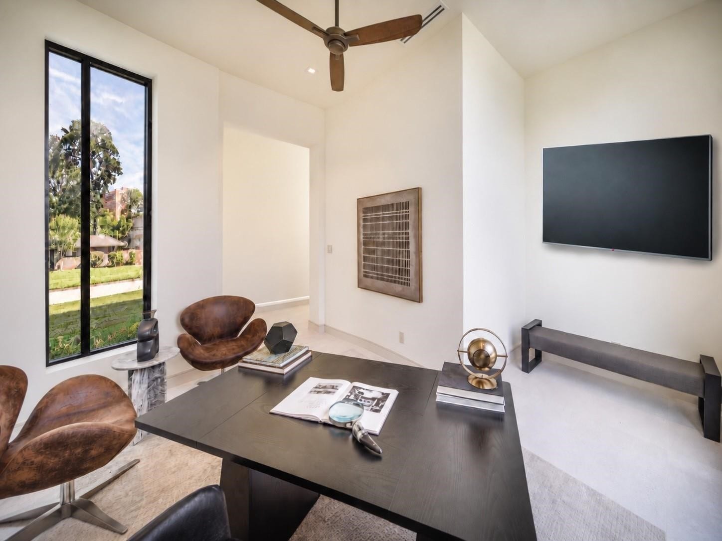 Where business meets confort. An alternative view of the home office designed for multitasking, with a dedicated screen perfect for monitoring the markets, catching the latest news or enjoying TV while you work, all framed by outdoor views. TV on the wall is virtually staged.