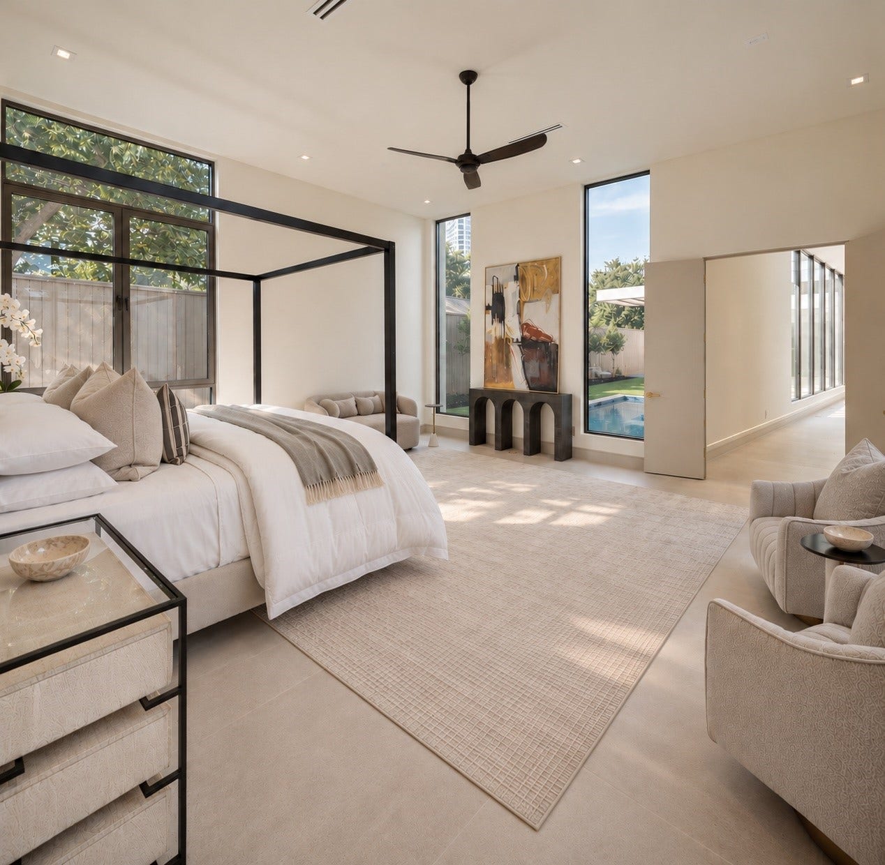Wake up to a resort-like outlook. This alternate view of the primary bedroom captures its generous scale, abundant natural light, and beautiful connections to the pool just beyond the windows.