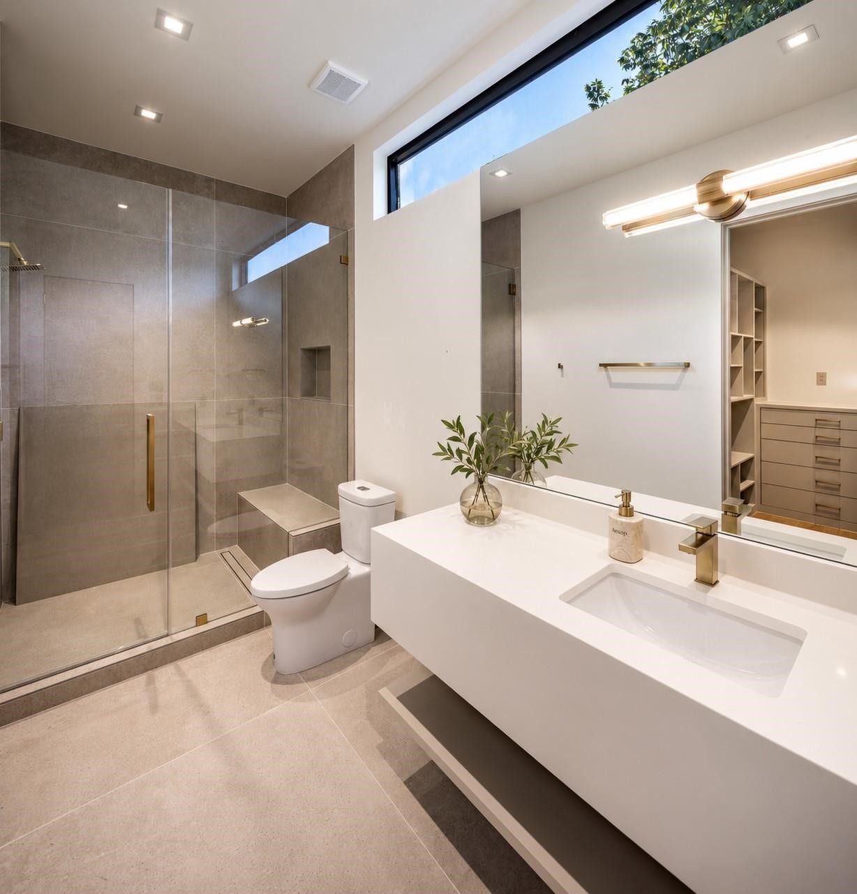 En-suite secondary guest bath with primary-suite polish. Clean lines, a floating vanity, oversized walk-in shower with bench, and clerestory window that brings in natural light while maintaining privacy. Sophisticted and beautifully appointed for guests.