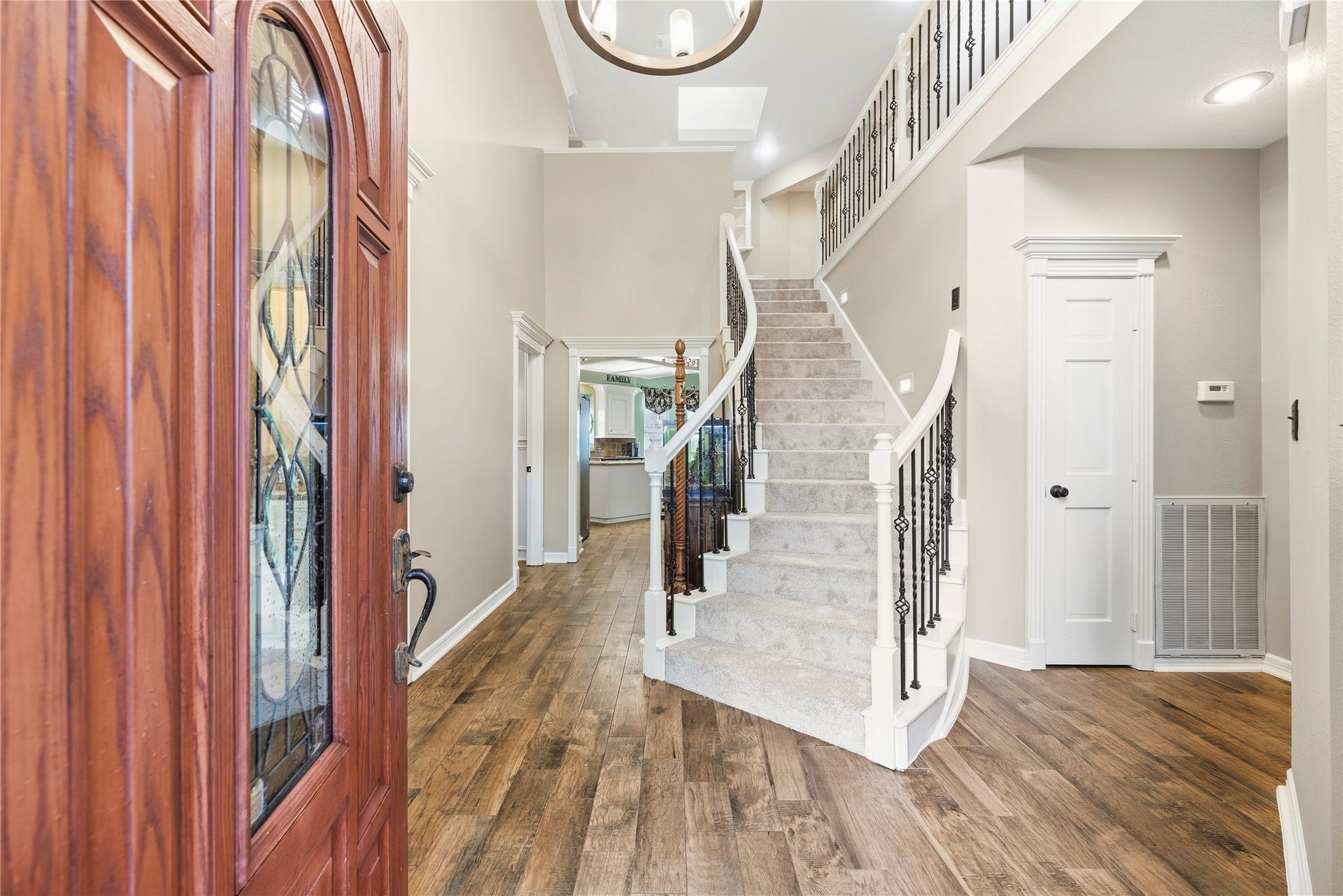 13114 S Winesap Lane, Cypress, TX 77429 Elegant entryway featuring a grand staircase with wrought iron accents, warm wood flooring, and high ceilings that create a welcoming and spacious atmosphere.