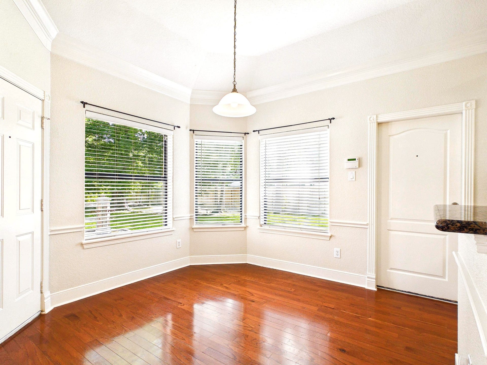 19521 Desna Drive, Porter, TX 77365 Bright and inviting breakfast area with large windows, hardwood floors, and neutral walls. It features a central light fixture and ample natural light, creating a warm and open atmosphere.