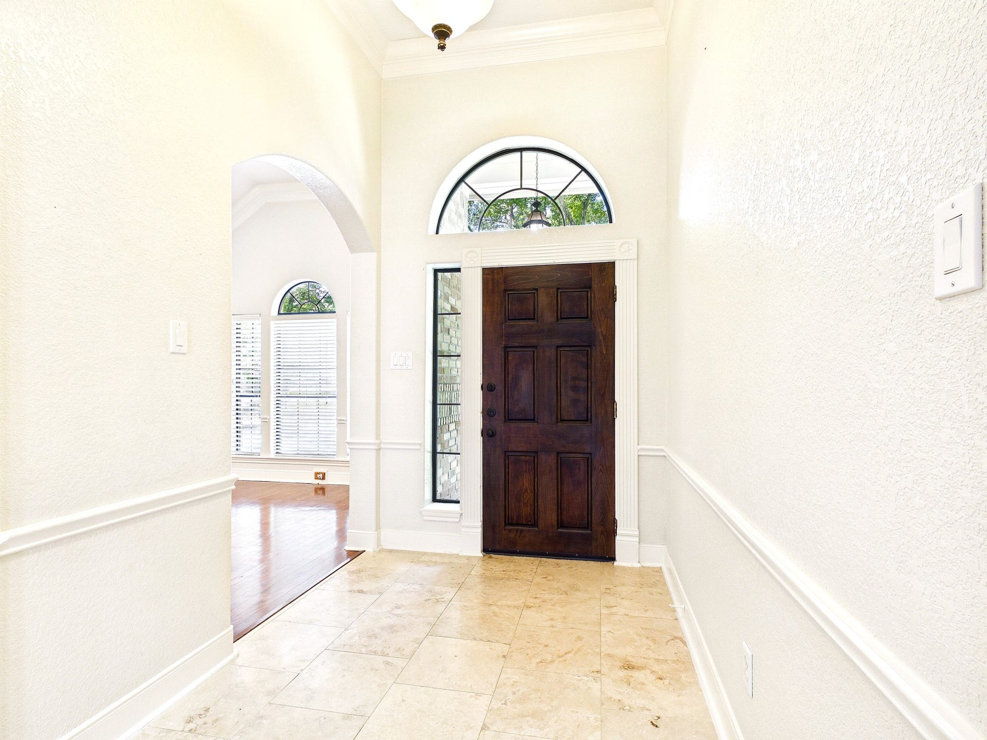 19521 Desna Drive, Porter, TX 77365 Bright and welcoming entryway with a solid wood front door, arched window, and tile flooring. The space leads to a room with hardwood floors and abundant natural light.