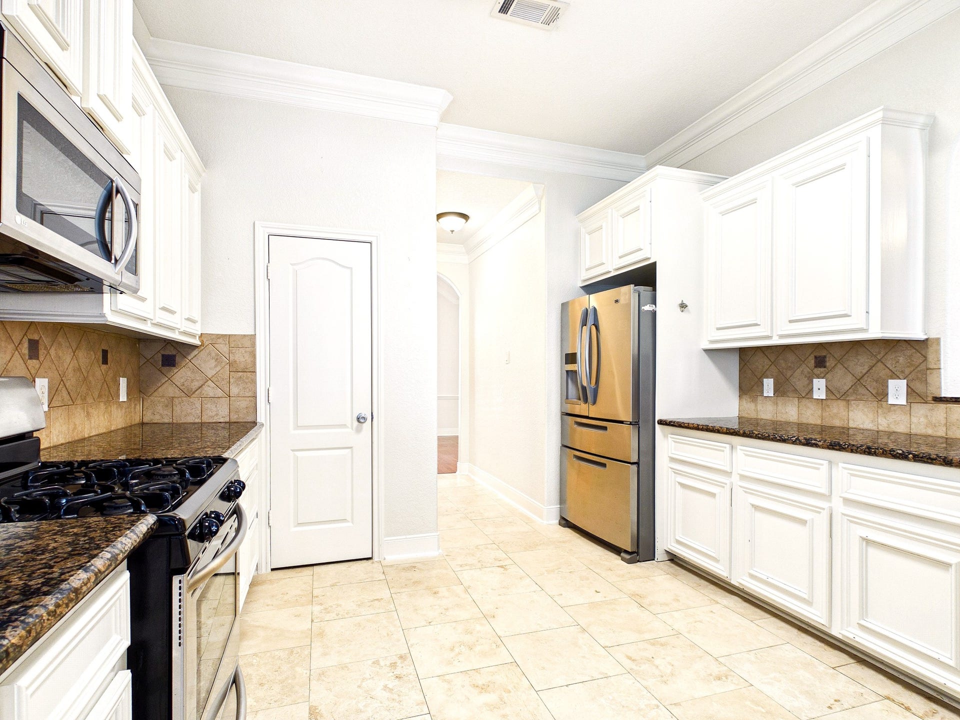 19521 Desna Drive, Porter, TX 77365 This kitchen features white cabinetry, granite countertops, and stainless steel appliances. The tiled backsplash and flooring add a touch of elegance, while the layout offers ample storage and workspace.