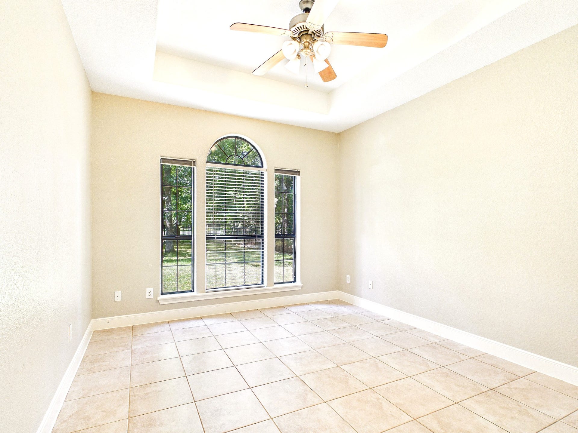 19521 Desna Drive, Porter, TX 77365 This bedroom features a large arched window offering ample natural light, neutral walls, tiled flooring, and a ceiling fan, creating a nice bright space.