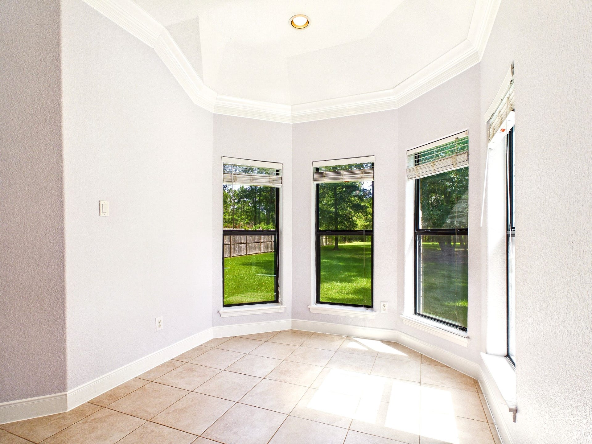 19521 Desna Drive, Porter, TX 77365 This bright, inviting area features large windows with views of a lush backyard, tiled floors, and a high ceiling with elegant molding, perfect for a sunlit, cozy sitting area in the primary retreat.