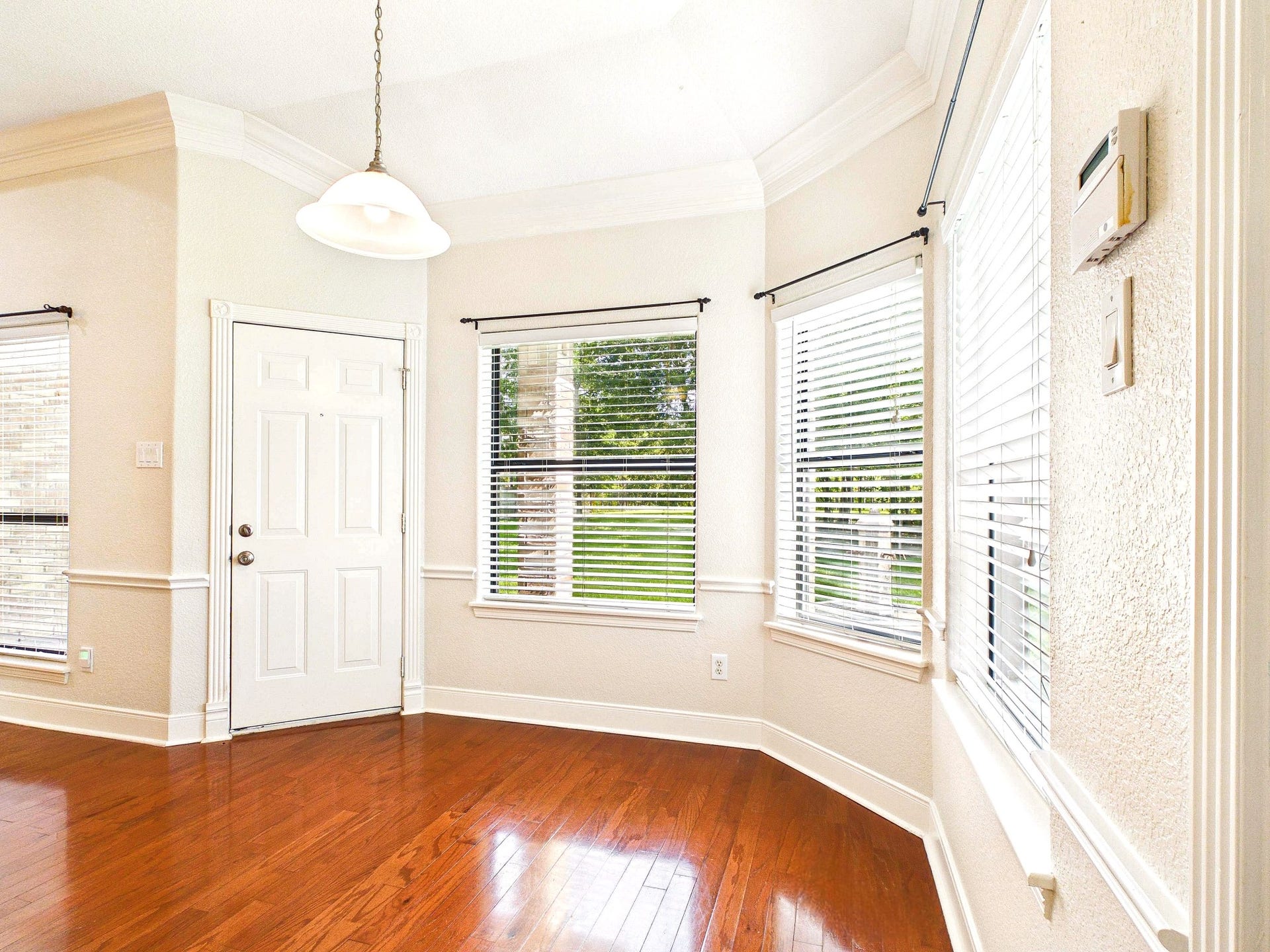 19521 Desna Drive, Porter, TX 77365 This bright breakfast dining area features hardwood floors, a classic white door, and large windows with blinds, offering plenty of natural light and a welcoming atmosphere.