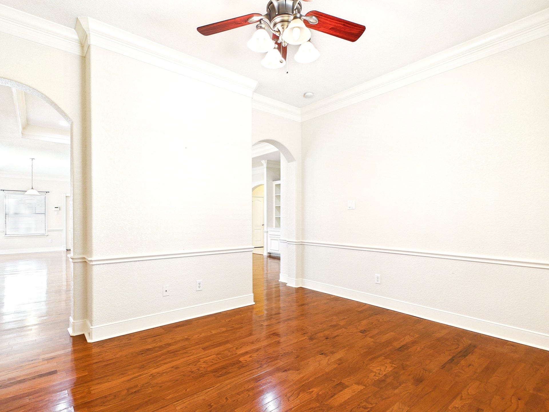 19521 Desna Drive, Porter, TX 77365 This bright room features hardwood floors, neutral walls, crown molding, and a ceiling fan. It has arched doorways leading to adjacent spaces, creating an open and airy feel. Providing flexible space for an office/den or a 4th bedroom.