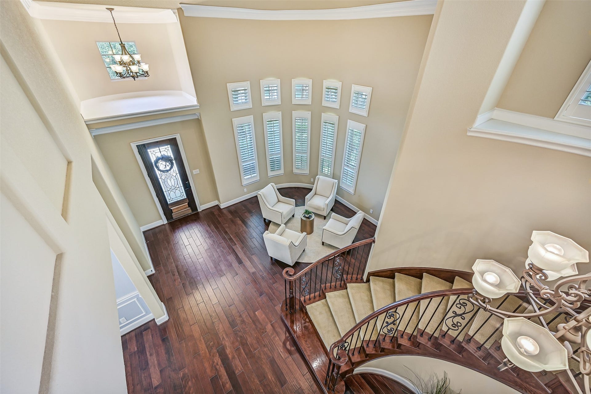 2304 Halls Creek Court, Friendswood, TX 77546 A dramatic birds-eye view showcases the homes impressive two-story entry, sweeping curved staircase with wrought iron balusters, rich wood flooring, and a wall of towering windows that flood the foyer with natural light.
