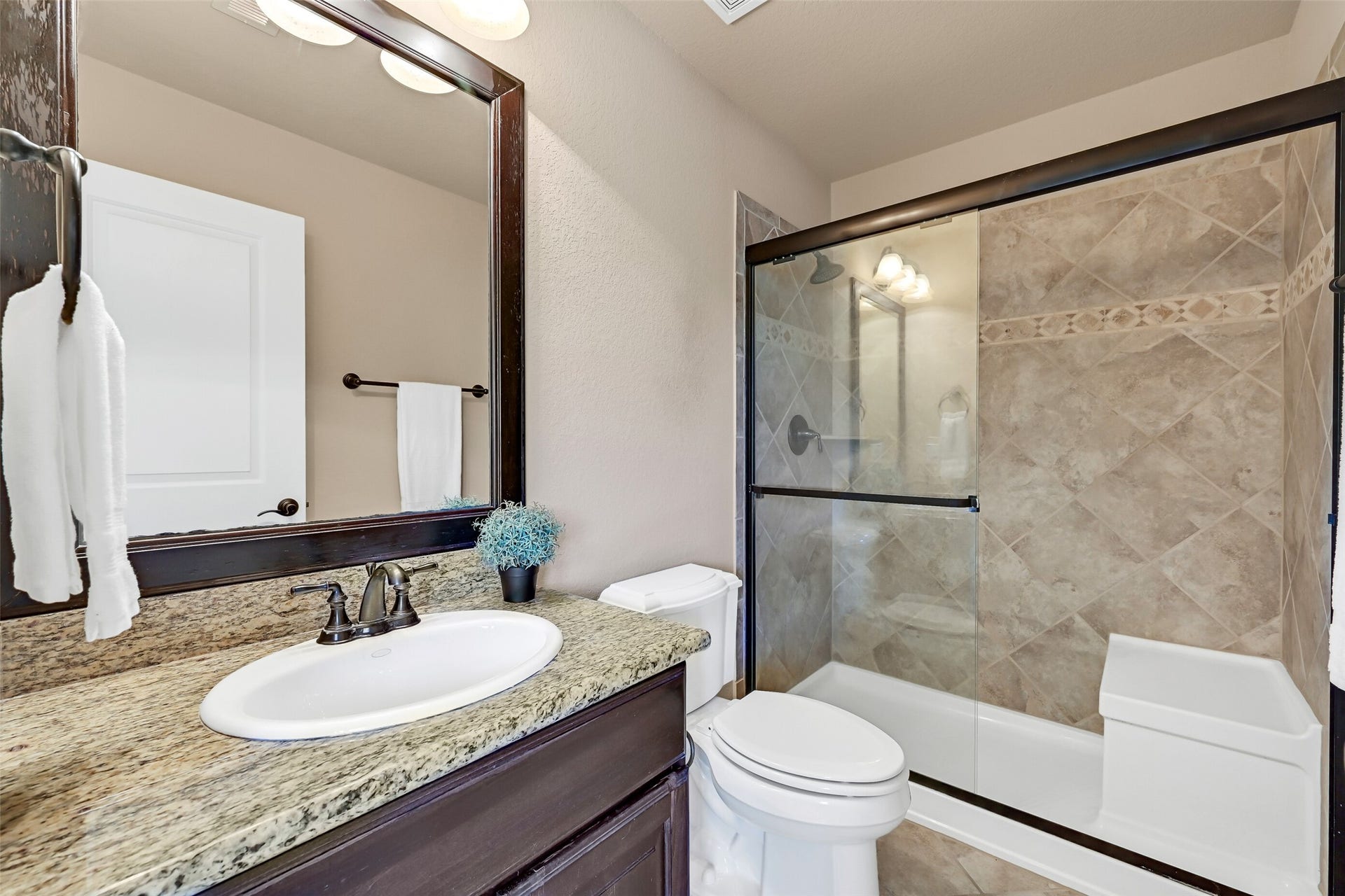 2304 Halls Creek Court, Friendswood, TX 77546 The en suite bathroom is finished with granite countertops, dark wood cabinetry, oil-rubbed bronze fixtures, and a tiled tub/shower combination that complements the homes upscale finishes. This bathroom is also accessible from the nearby game room.