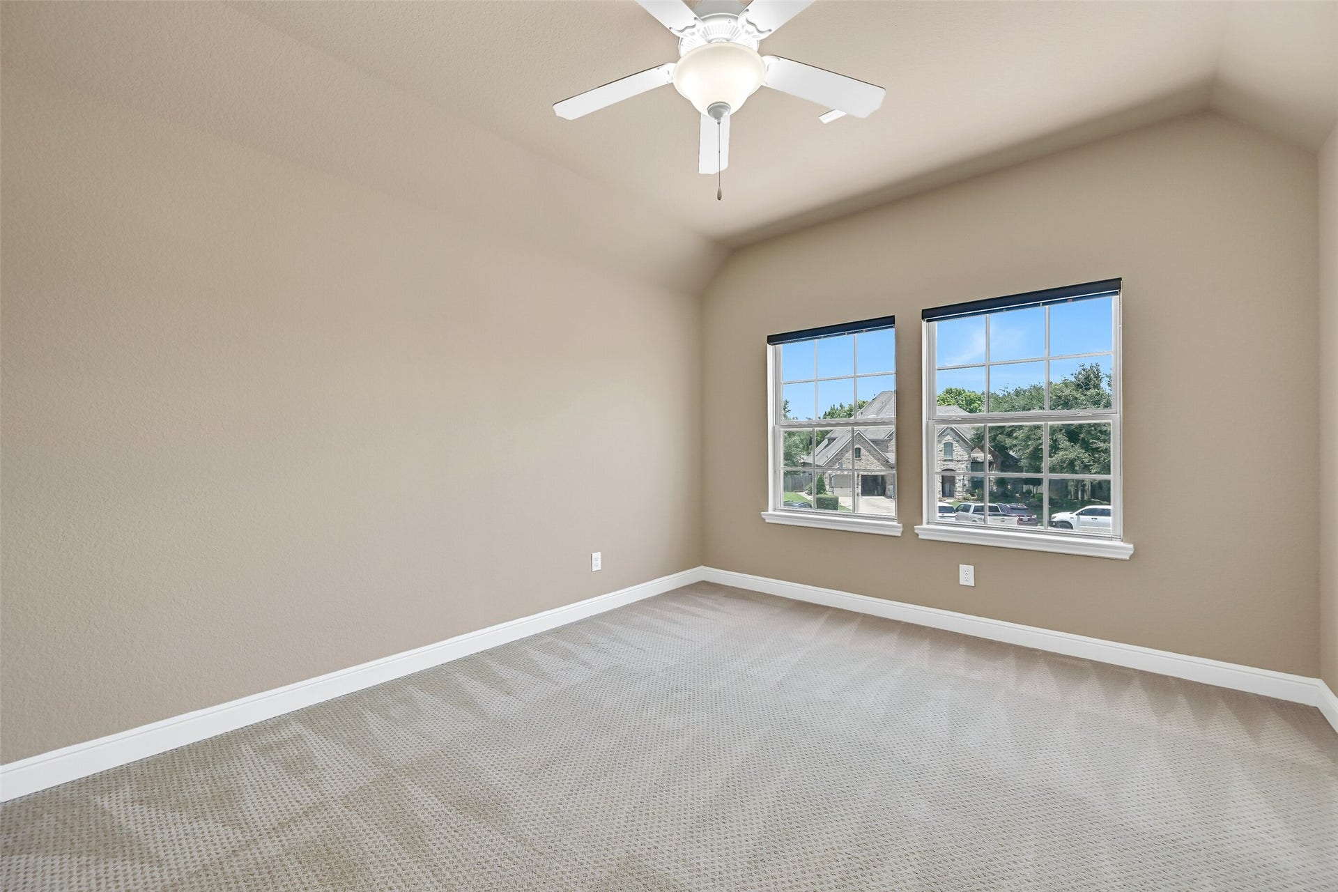 2304 Halls Creek Court, Friendswood, TX 77546 Another upstairs secondary bedroom offers raised gambrel ceilings with a lighted ceiling fan, plush sculpted carpet, and large front-facing windows overlooking the neighborhood, creating a welcoming space for family or guests.
