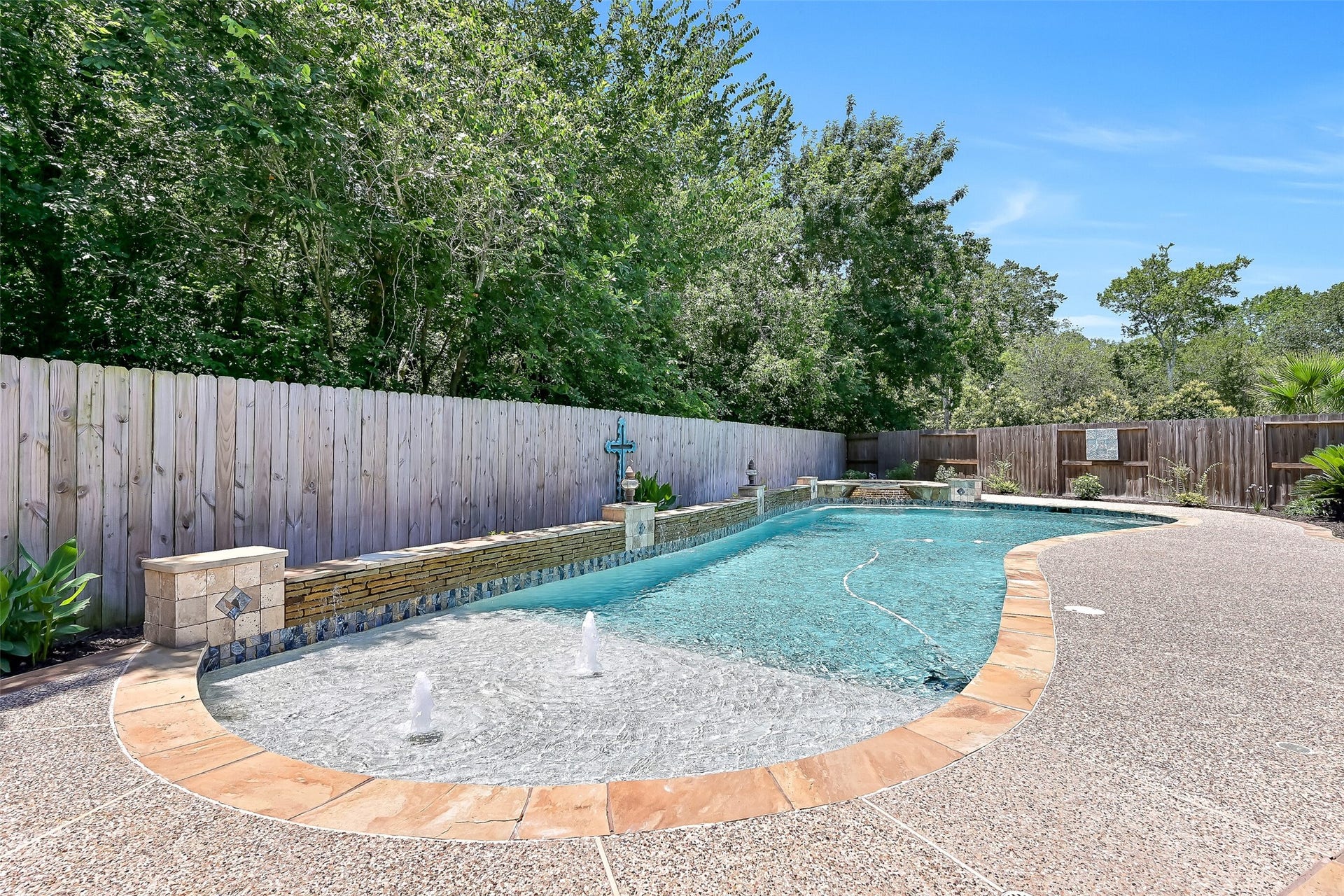 2304 Halls Creek Court, Friendswood, TX 77546 Designed for entertaining, the custom pool features a spacious 9x12 tanning ledge with bubblers and an umbrella holder, upgraded wet-edge premium pebble plaster, and a dramatic stacked flagstone weeping wall with water features.