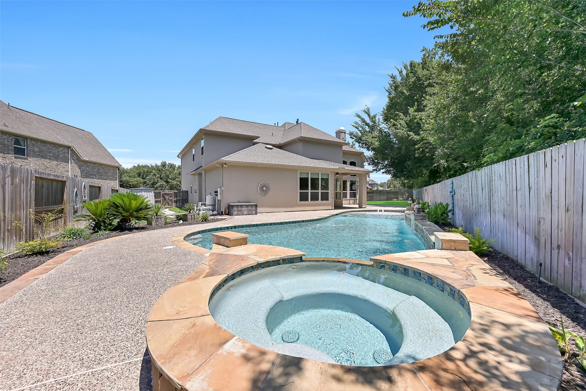 2304 Halls Creek Court, Friendswood, TX 77546 The oversized 7 spa comfortably accommodates 57 people and flows seamlessly into the pool, while the deep end includes a convenient second staircase for easy access.