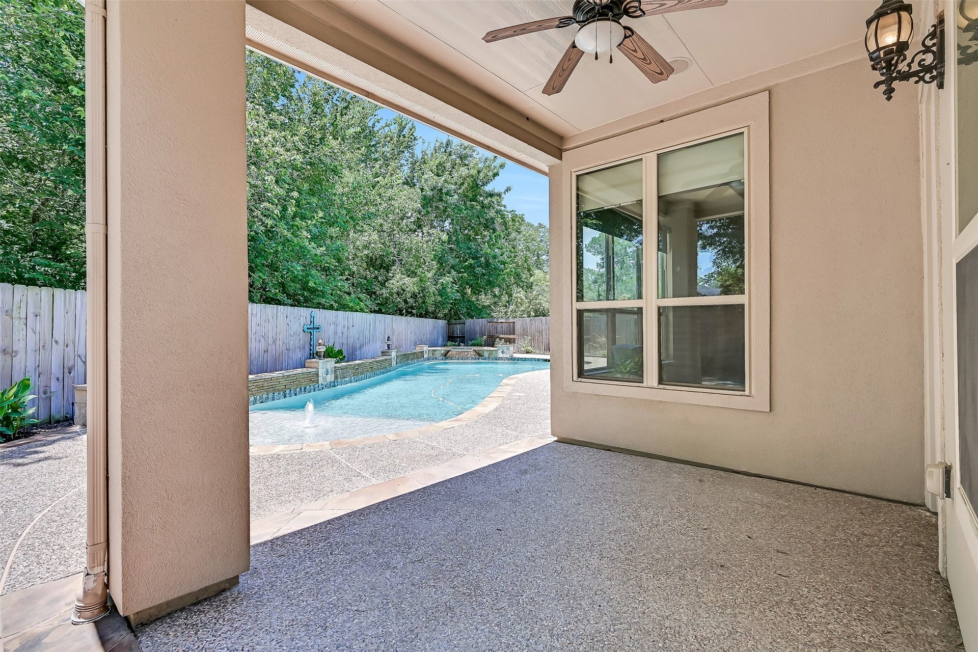 2304 Halls Creek Court, Friendswood, TX 77546 The covered back patio creates a comfortable outdoor living space with a ceiling fan, recessed lighting, built-in speakers, and peaceful views overlooking the resort-style pool and private backyard retreat.