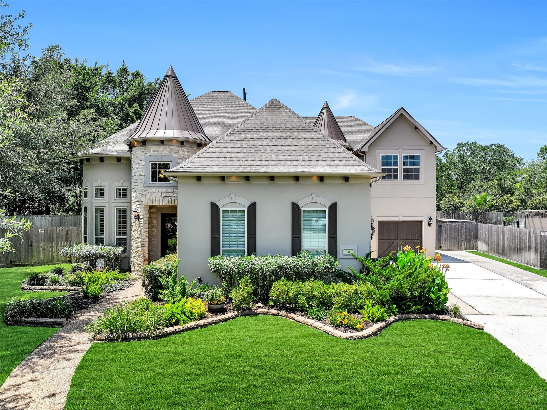 2304 Halls Creek Court, Friendswood, TX 77546 Tucked away on a beautifully landscaped cul-de-sac lot in West Ranch, this custom stucco home immediately stands apart with its stone turret accents, dramatic metal rooflines, carriage-style garage doors, lantern lighting, and meticulously maintained grounds that create unforgettable curb appeal from the street.
