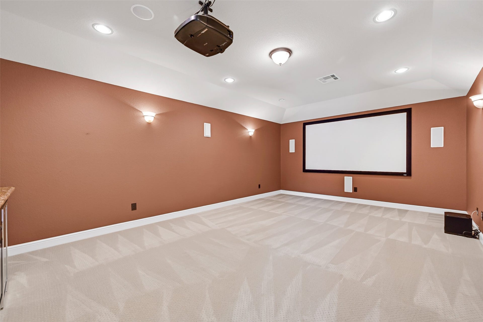 2304 Halls Creek Court, Friendswood, TX 77546 Designed for the ultimate cinematic experience, the dedicated media room features dimmable sconce lighting, recessed lighting, an existing projector and screen setup, built-in surround sound speakers, and ample space for theater-style seating.