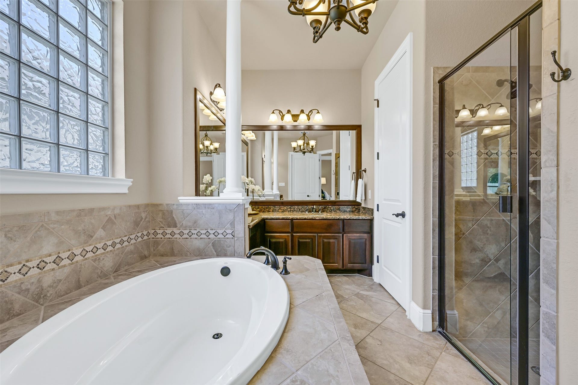 2304 Halls Creek Court, Friendswood, TX 77546 Another angle of the primary bath highlights the oversized soaking tub, glass-enclosed shower with tile surround, framed mirrors, and the thoughtful split-vanity layout that allows the space to function beautifully for everyday routines.