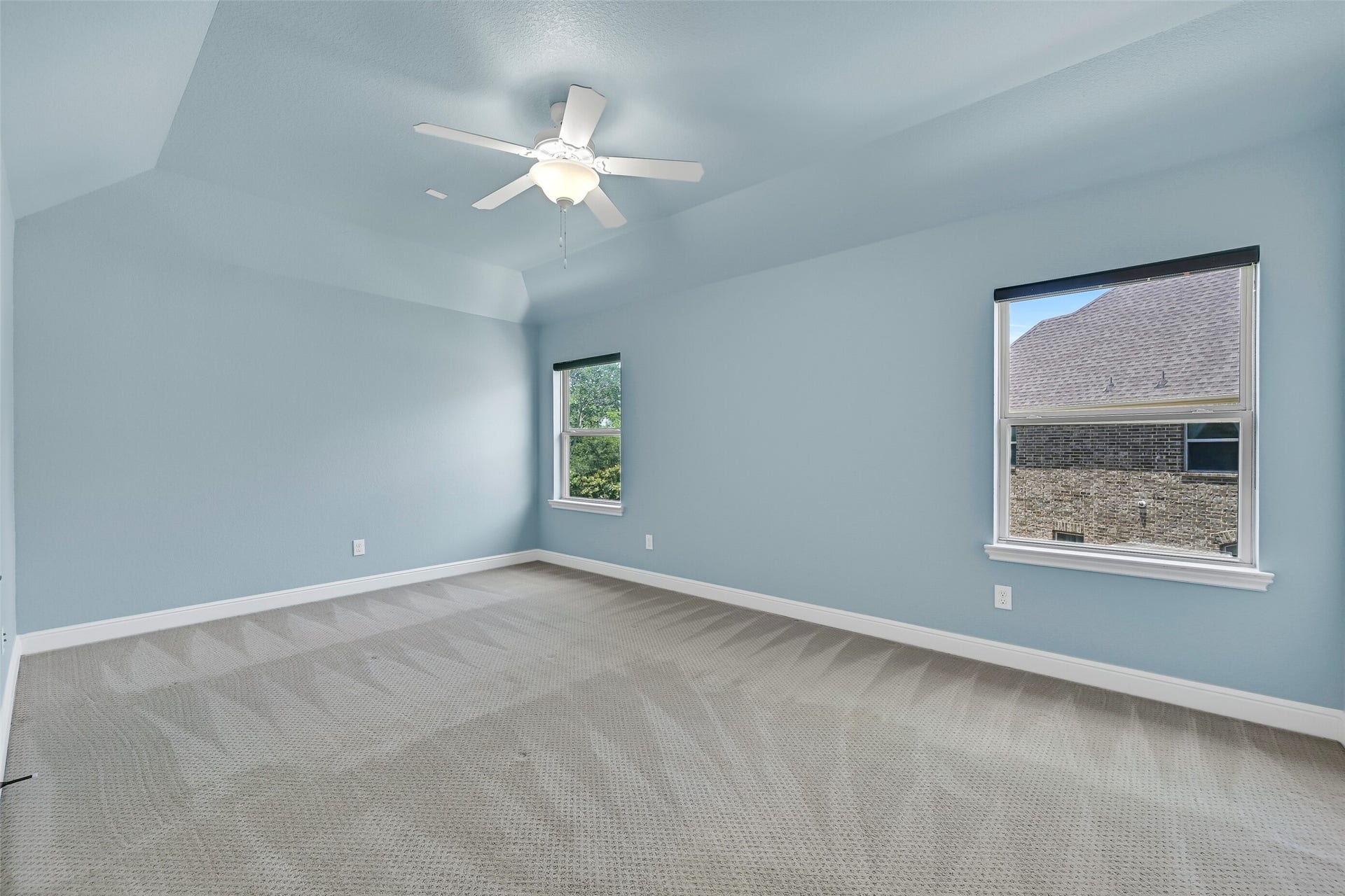 2304 Halls Creek Court, Friendswood, TX 77546 Soft blue walls andelevated gambrel ceilings give this secondary bedroom a bright, calming feel, while generous proportions provide plenty of space for larger furniture or a flexible study setup. A pair of side facing windows bring in natural light.
