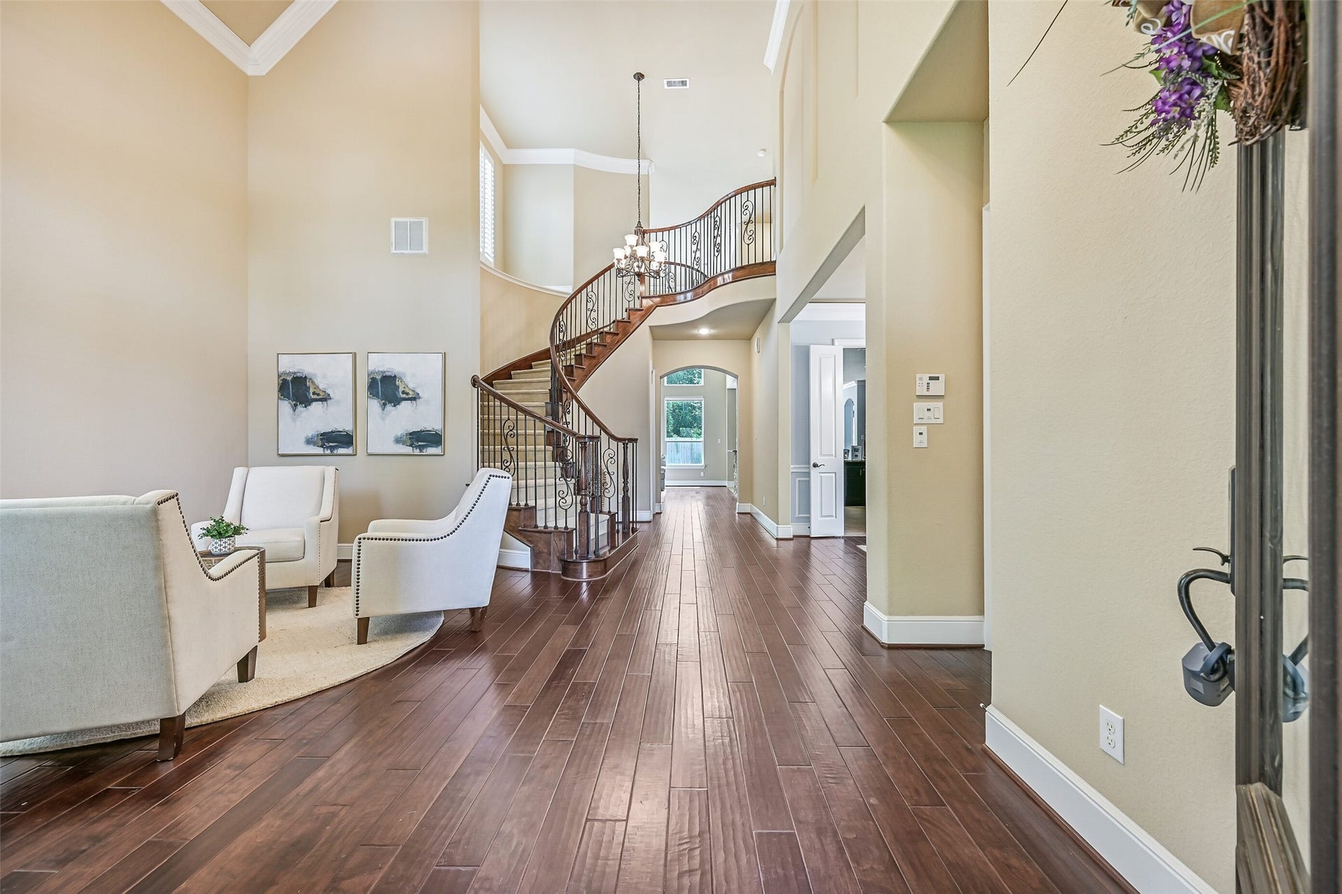 2304 Halls Creek Court, Friendswood, TX 77546 Step inside the grand foyer where soaring ceilings, engineered wood floors, and a dramatic curved staircase with iron balusters immediately set an elegant tone. A wall of towering windows trimmed with plantation shutters fills the space with natural light while highlighting the homes impressive architectural scale.