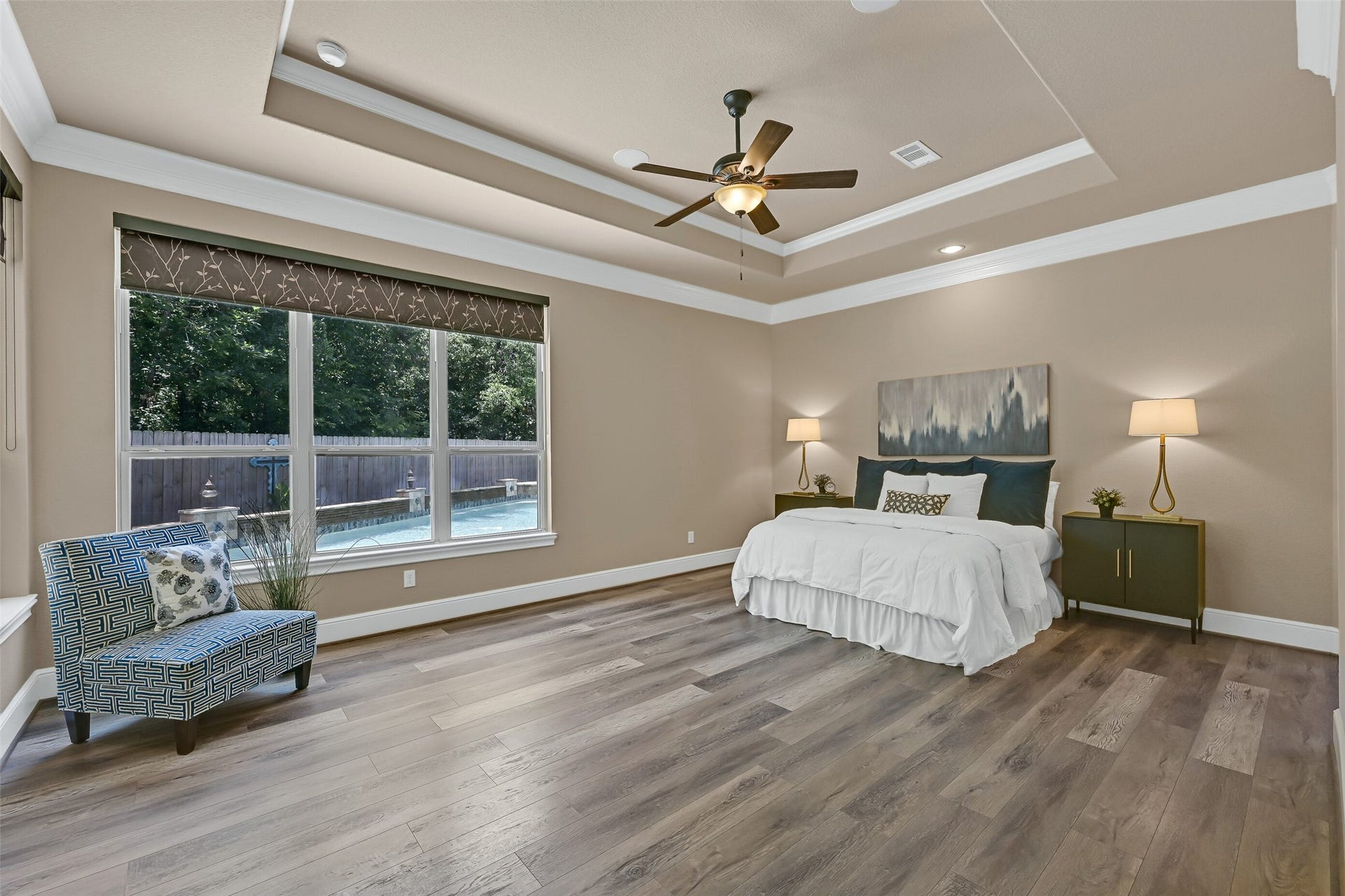 2304 Halls Creek Court, Friendswood, TX 77546 Tucked privately on the first floor, the owners retreat feels like a true sanctuary with a tray ceiling, crown molding, built-in speakers, luxury vinyl plank flooring, and large windows overlooking the pool and backyard. Custom shades and the generous room size create a calm, comfortable atmosphere with plenty of space to unwind.