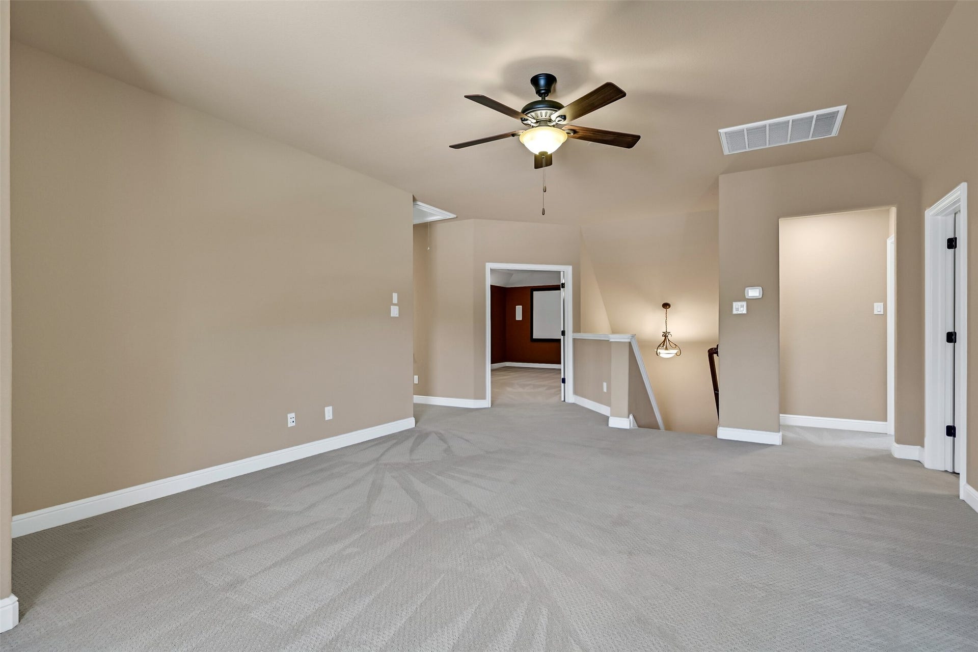 2304 Halls Creek Court, Friendswood, TX 77546 Another angle highlights the expansive scale of the game room and its open connection to the upper level, creating the perfect gathering space for entertaining or everyday relaxation. Here, you'll catch a glimpse of the rear staircase and the double door entrance to the media room.