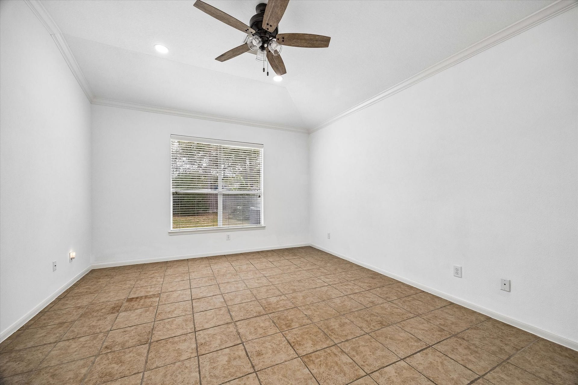 6741 Hidden Colony Lane, Dickinson, TX 77539 Spacious primary bedroom with vaulted ceilings, neutral tile flooring, and a large window offering natural light and a view of the backyard.