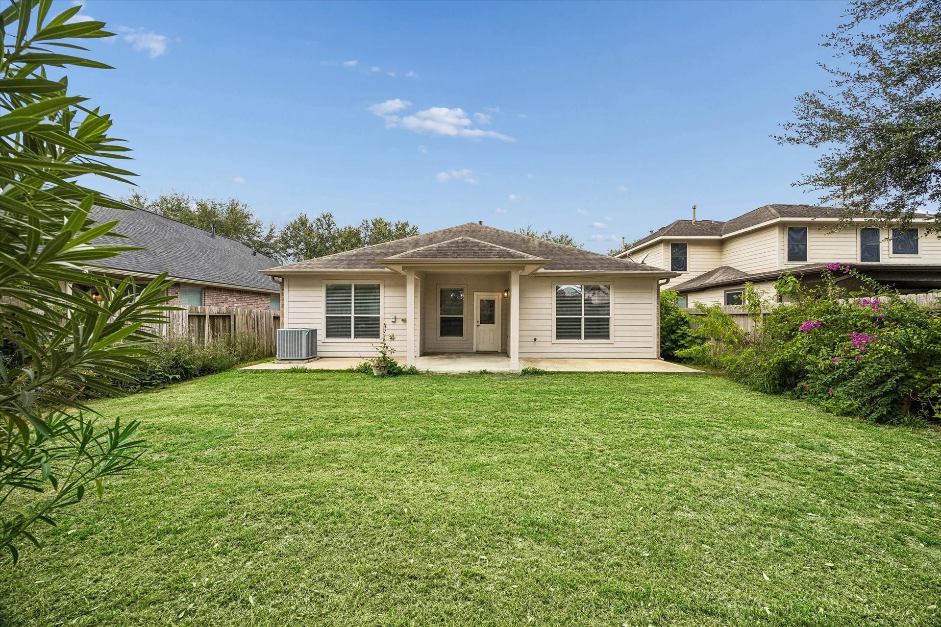 6741 Hidden Colony Lane, Dickinson, TX 77539 Discover a spacious backyard oasis, beautifully framed by vibrant perennial flowering plants, perfect for relaxation and outdoor gatherings.