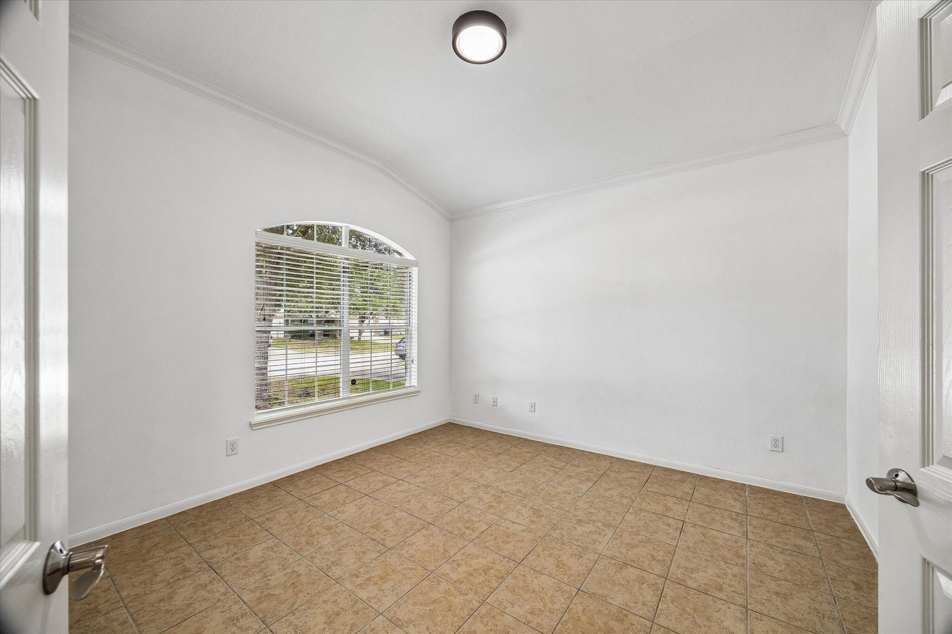 6741 Hidden Colony Lane, Dickinson, TX 77539 Bright and inviting room with large arched window, neutral tile flooring, and crisp white walls, perfect for a cozy study or home office.