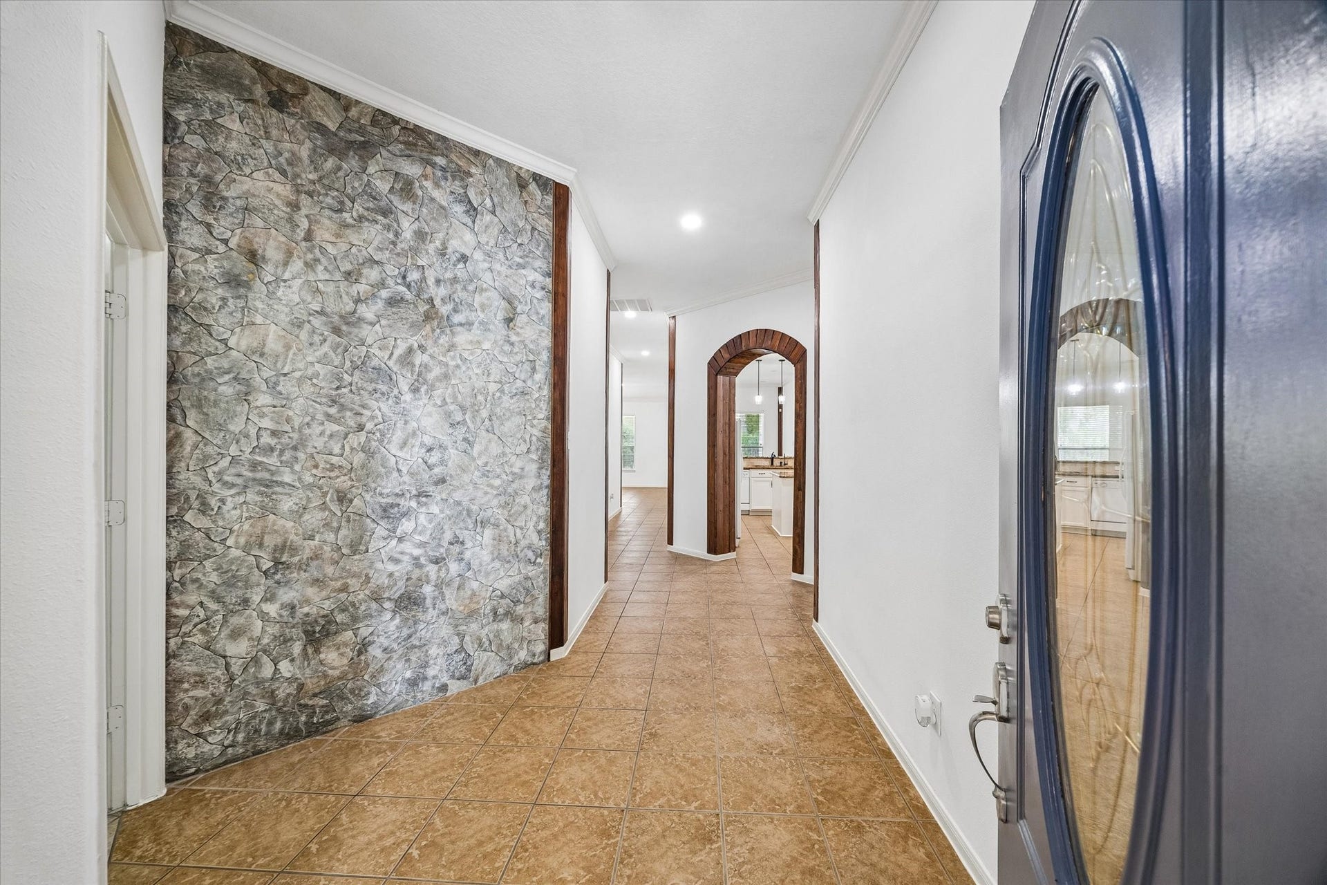 6741 Hidden Colony Lane, Dickinson, TX 77539 Inviting entryway with a unique stone-accented wall, warm tile flooring, and elegant archways leading to an open living space.