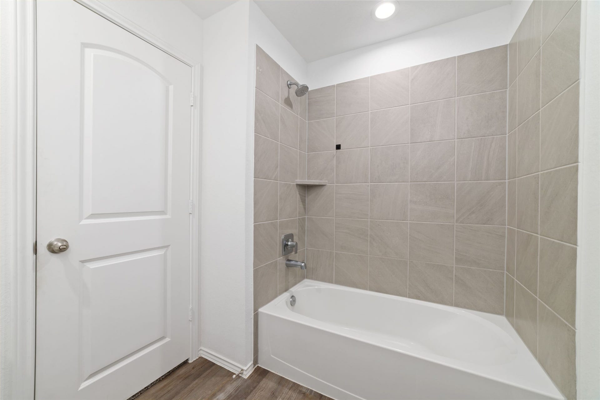 (Upstairs Full Bath): Crisp and spotless third full bathroom centrally positioned on the second floor to effortlessly service the game room and upstairs secondary bedrooms. This bright, move-in-ready space features dark wood-look flooring, a sleek white vanity with a seamless integrated sink, a large wall mirror, and a beautifully tiled shower/bathtub surround.