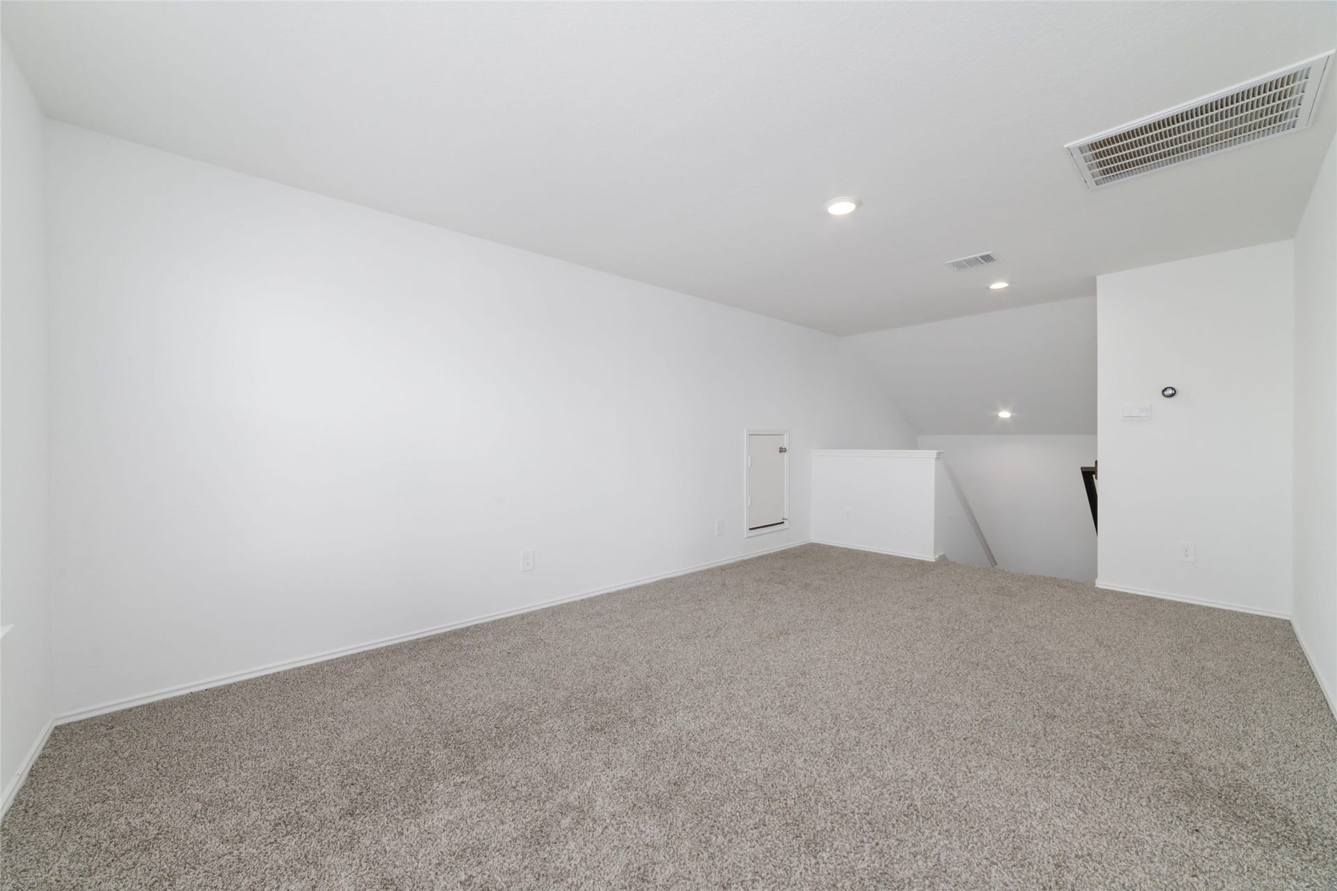 Located at the top of the stairs, this expansive and versatile upstairs game room offers a flexible bonus space ideal for a home theater, children's playroom, or casual secondary living area. The room features soft neutral carpeting, clean white walls, recessed lighting, and twin double windows that flood the open layout with abundant natural light while connecting seamlessly to the secondary bedrooms