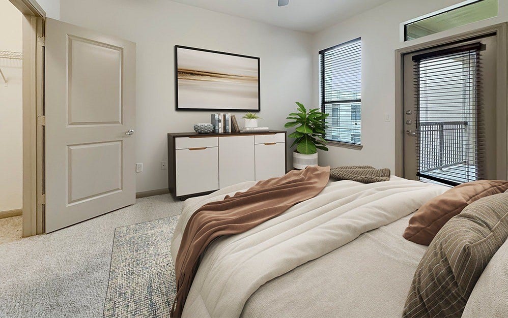 Bright and inviting bedroom featuring plush carpeting, generous natural light, and direct balcony access. A spacious closet provides convenient storage, while large windows enhance the airy feel of the room.