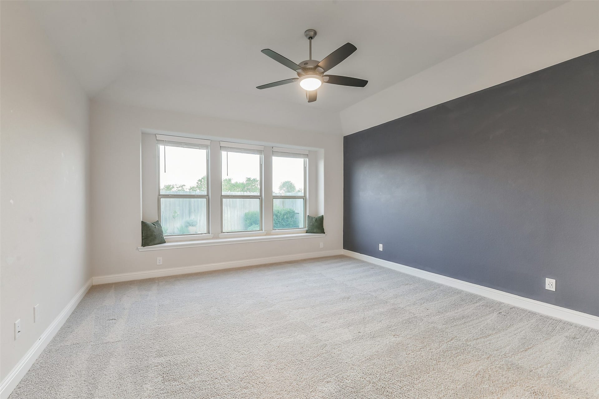 20330 Rose Gray Lane, Tomball, TX 77377 The primary bedroom features window seating, a ceiling fan, beautiful accent wall, and plenty of natural light from the windows with blinds for privacy.