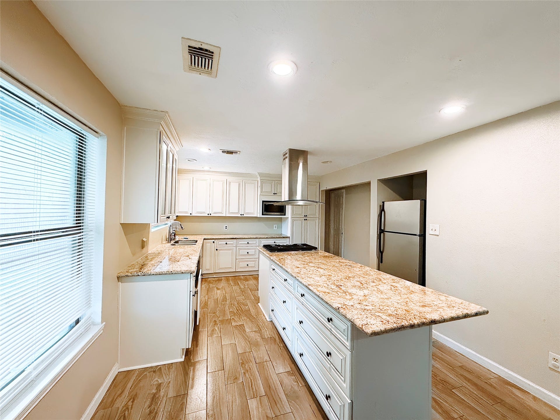 8116 Gulick Lane, Houston, TX 77075 Spacious kitchen featuring sleek granite countertops, modern stainless steel appliances, and warm wood flooring, perfect for culinary enthusiasts.